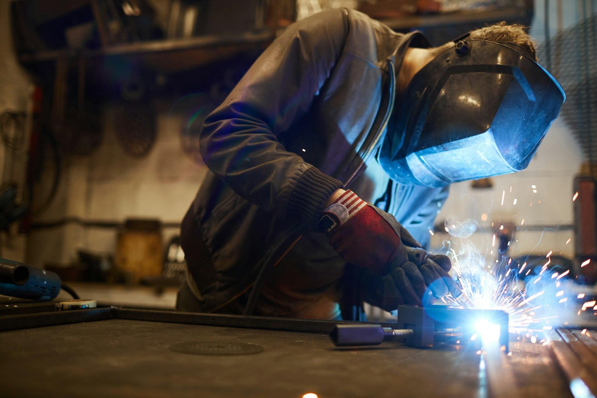 A welder wearing a protective helmet while working on a project.