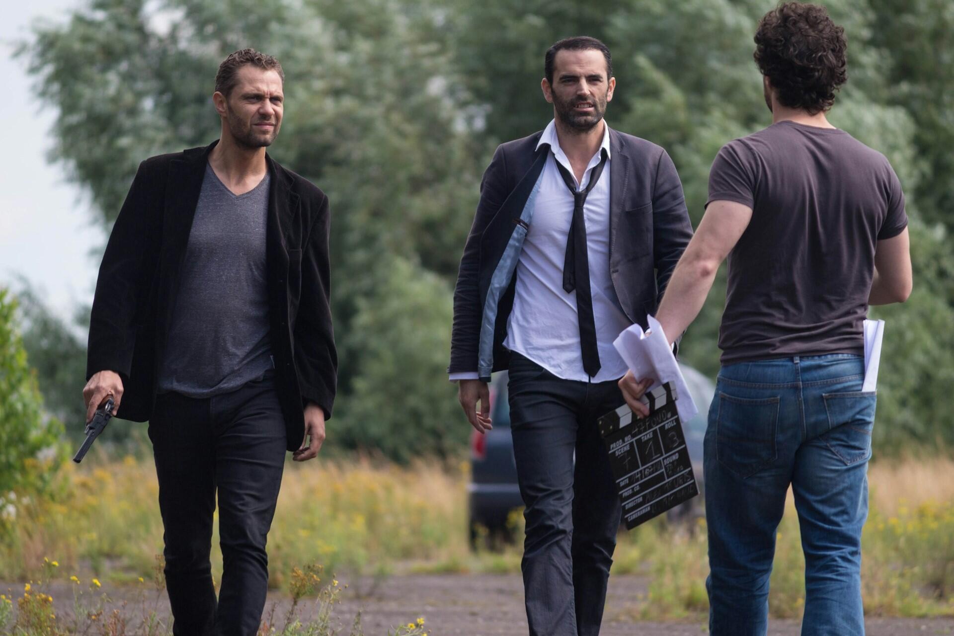 Three actors walking together on a film set while preparing for a scene