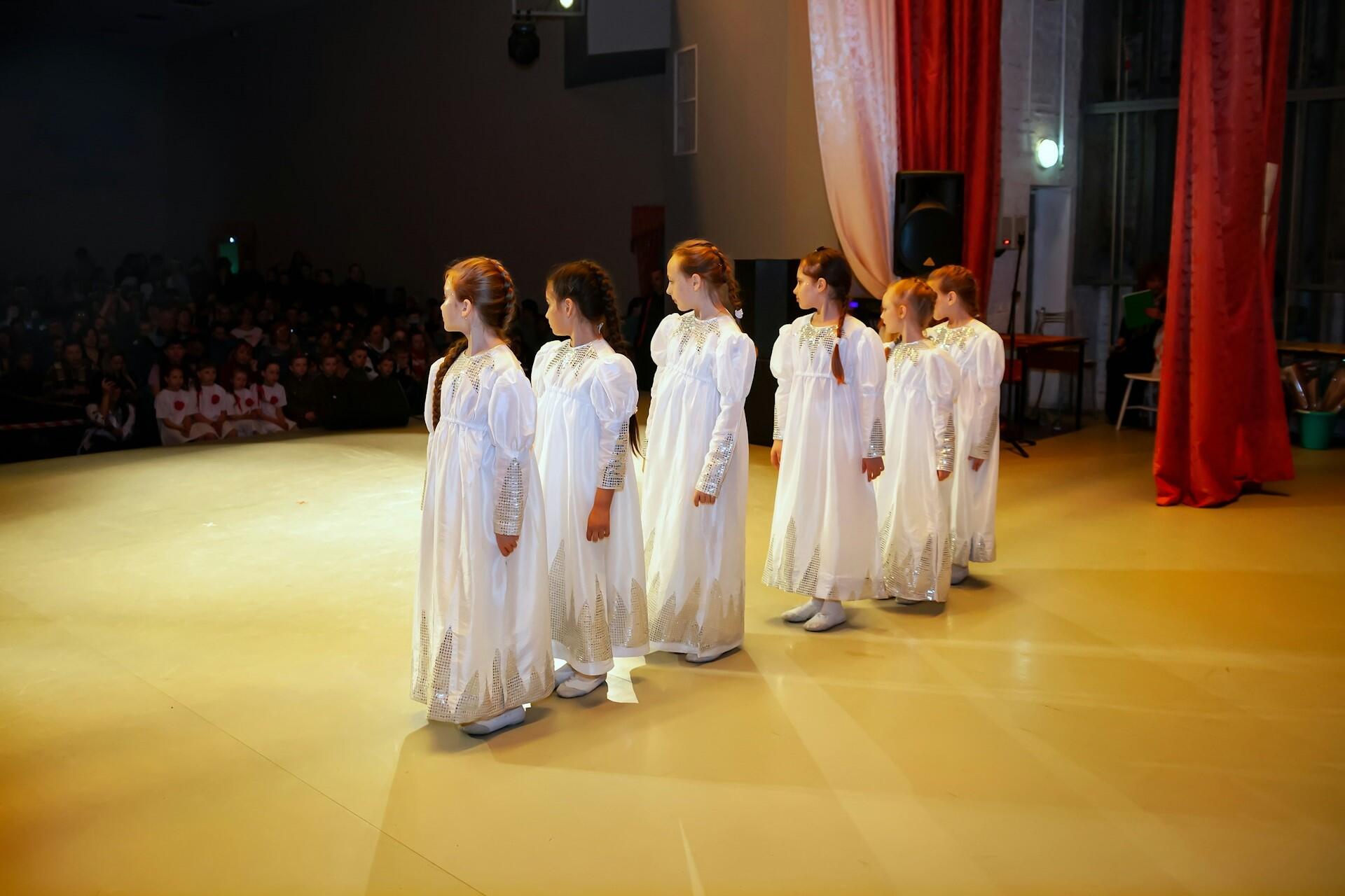Children performing in a choir on stage during a singing performance