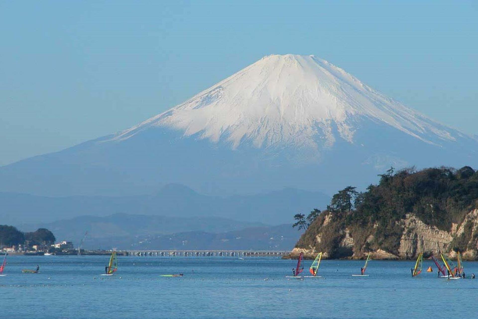 Snow-covered Mount Fuji rising above coastal waters during winter