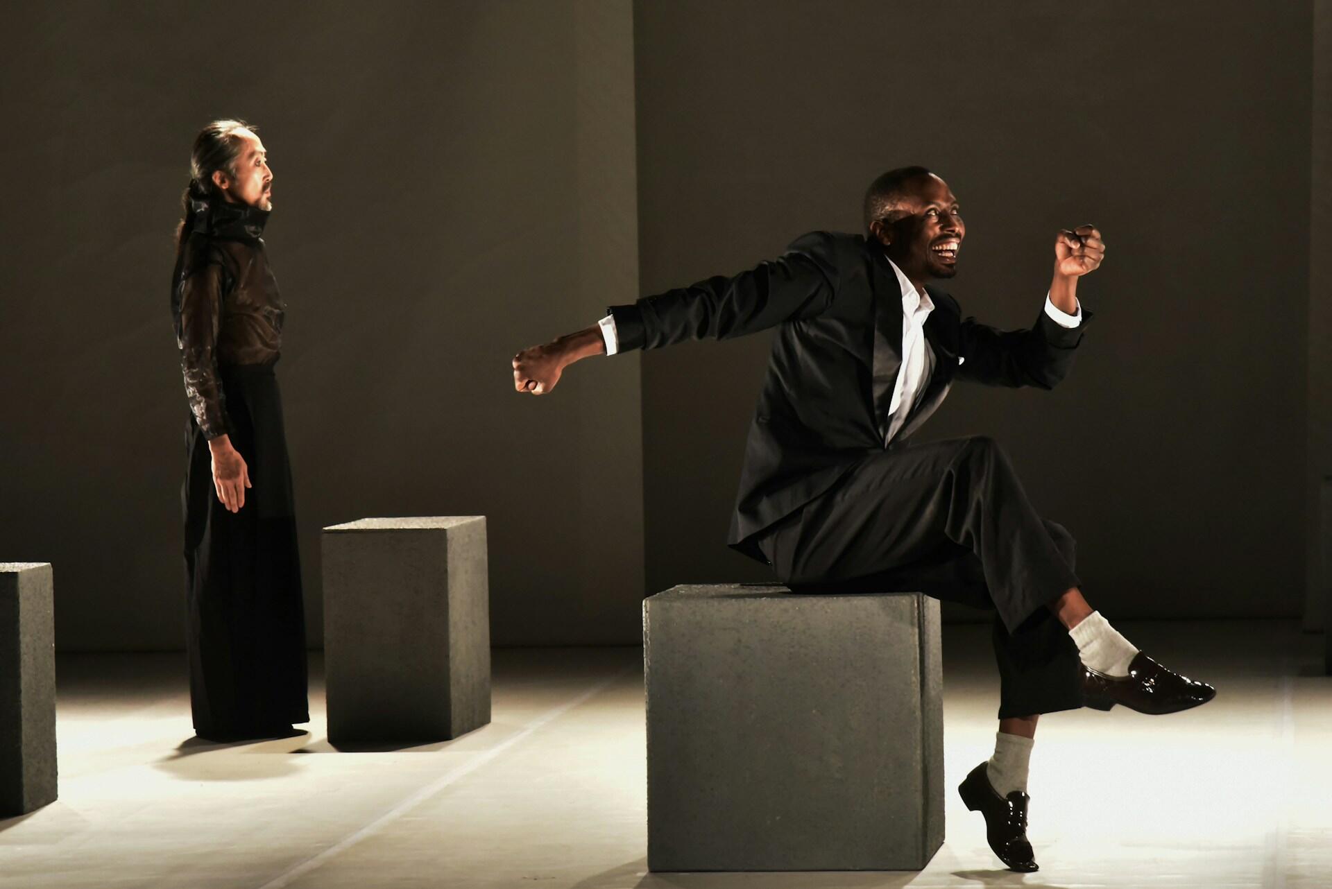 Two actors performing an expressive scene on a theatre stage