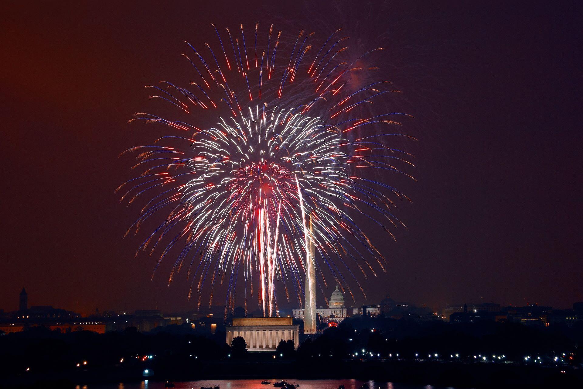 Fourth of July fireworks over Washington, D.C., with the Lincoln Memorial, Washington Monument, and U.S. Capitol visible at night.