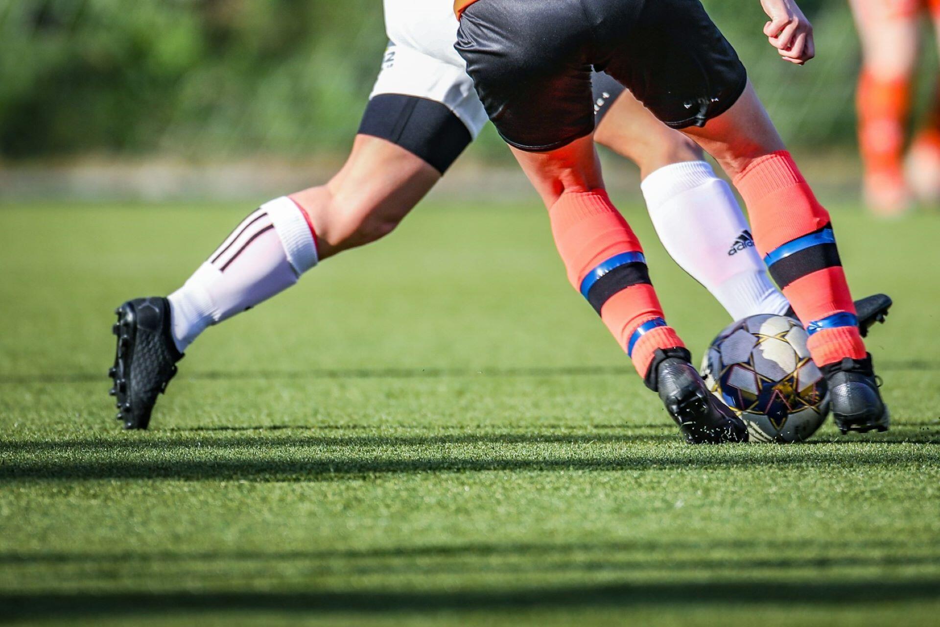 Soccer players challenging for the ball on an outdoor field.
