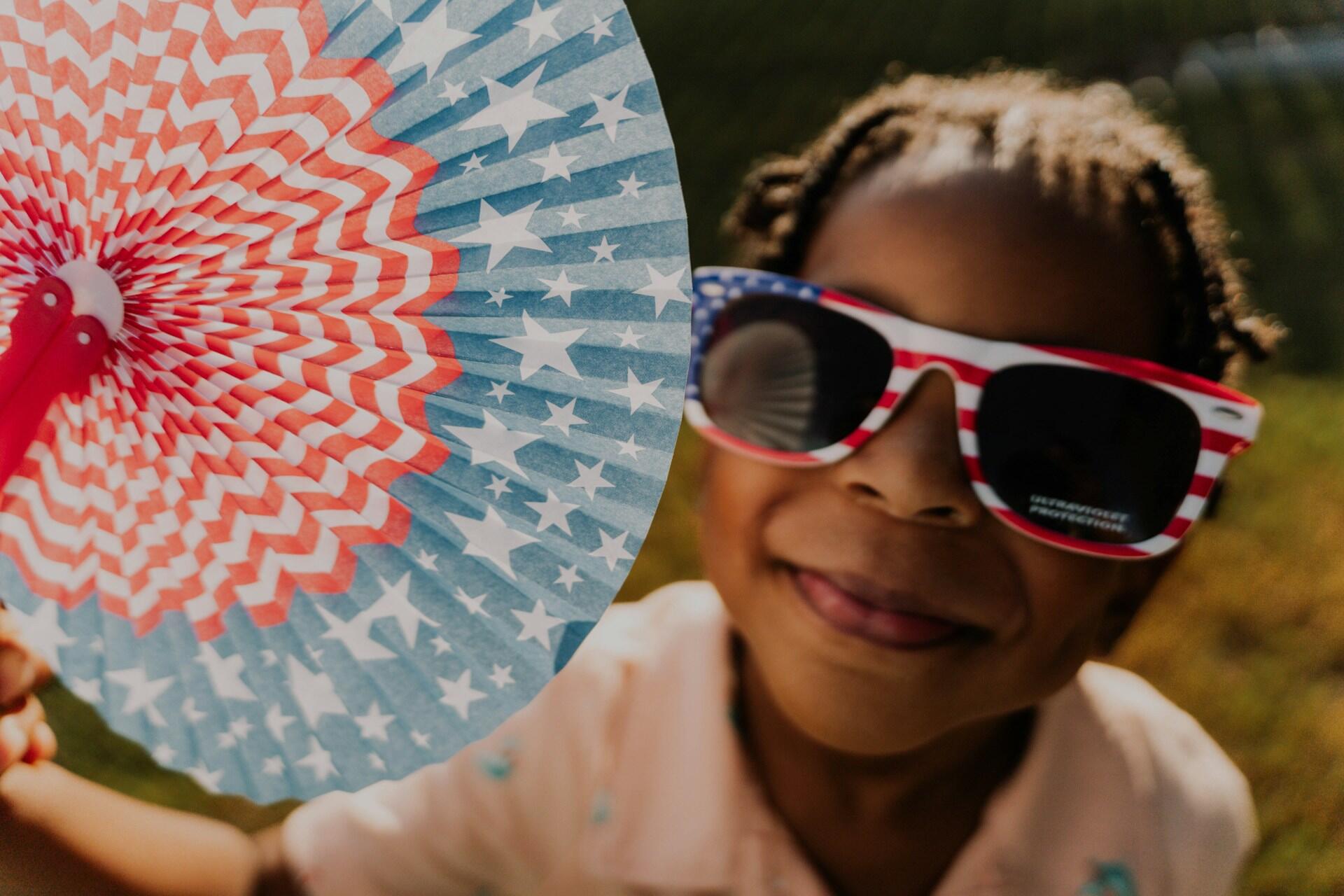 Kid playing with a 4th of July paper fan