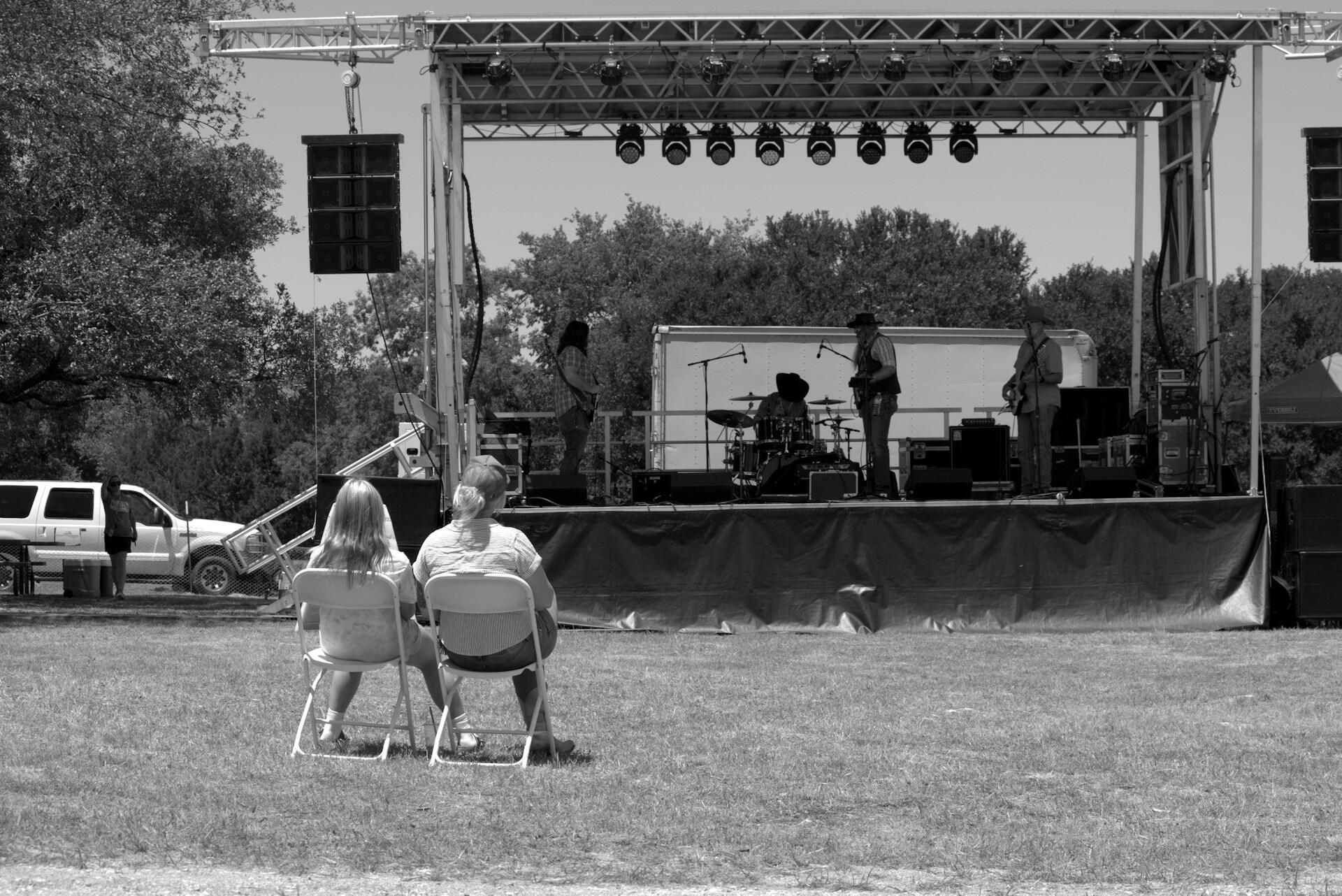Family gathered around a stage listening to music at a Fourth of July festival