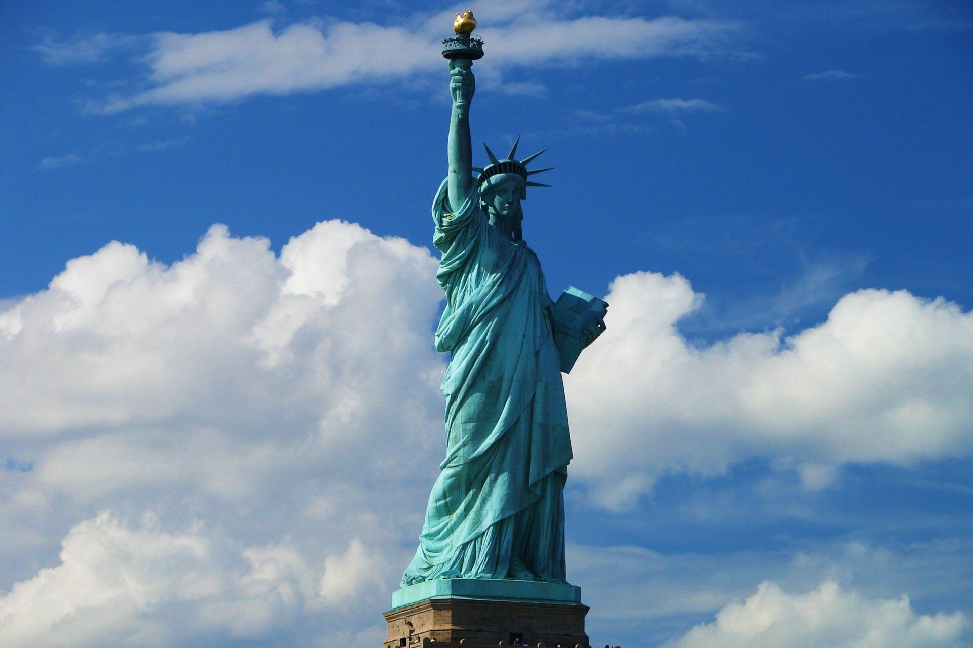 Statue of Liberty against a blue sky with clouds.