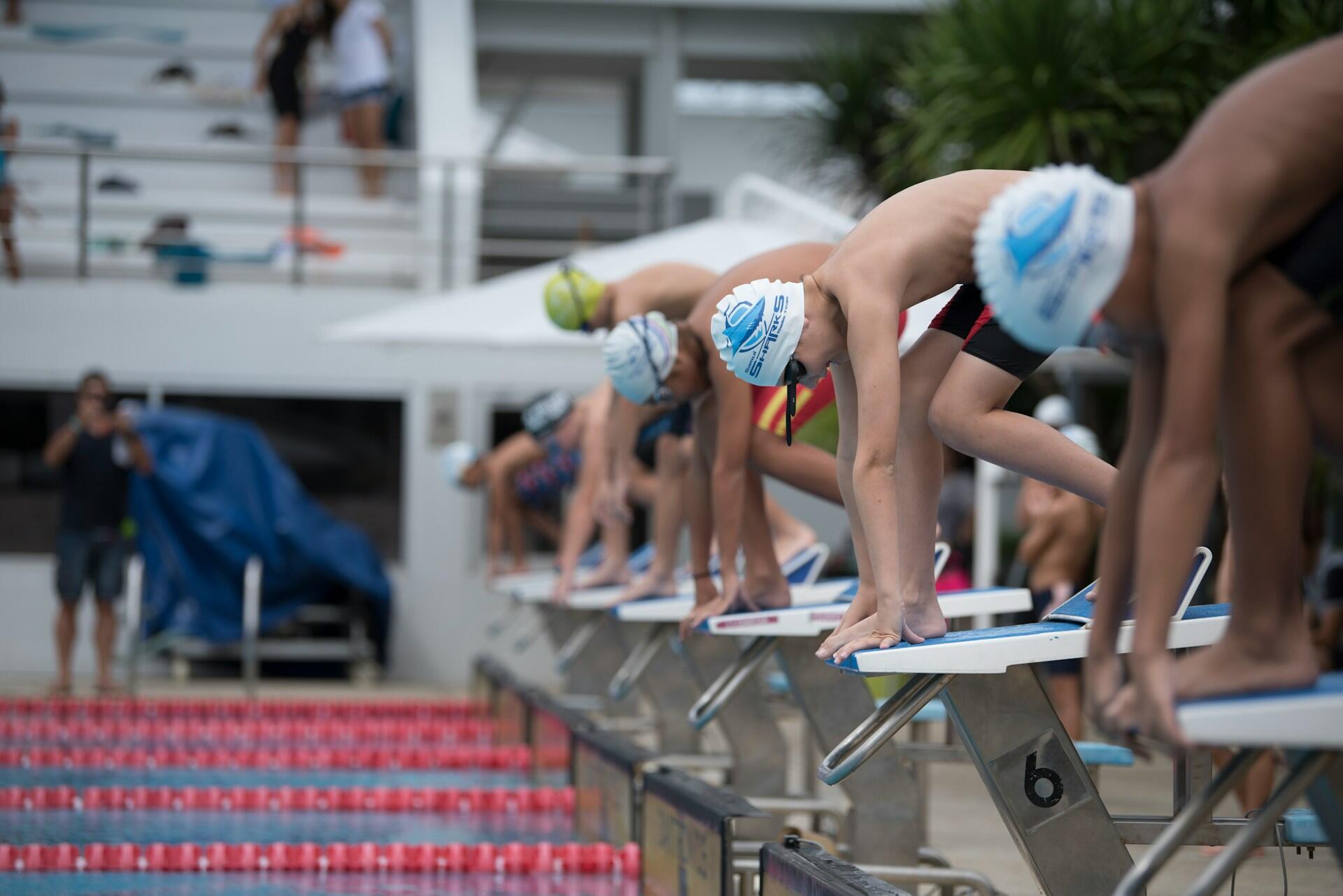 Men about to jump in the pool for a race