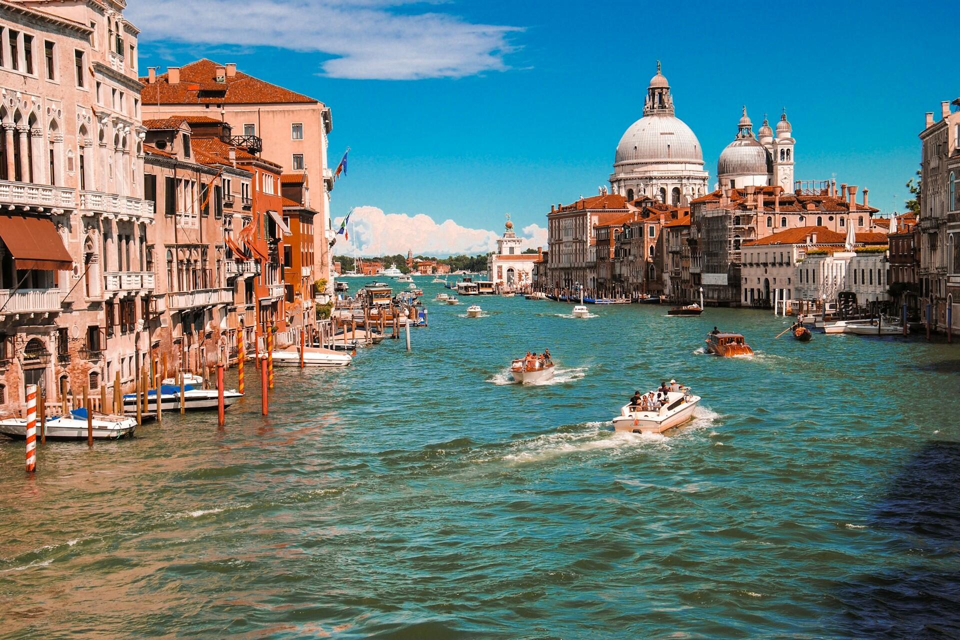 Boats on a canal in Venice with historic buildings and a domed church