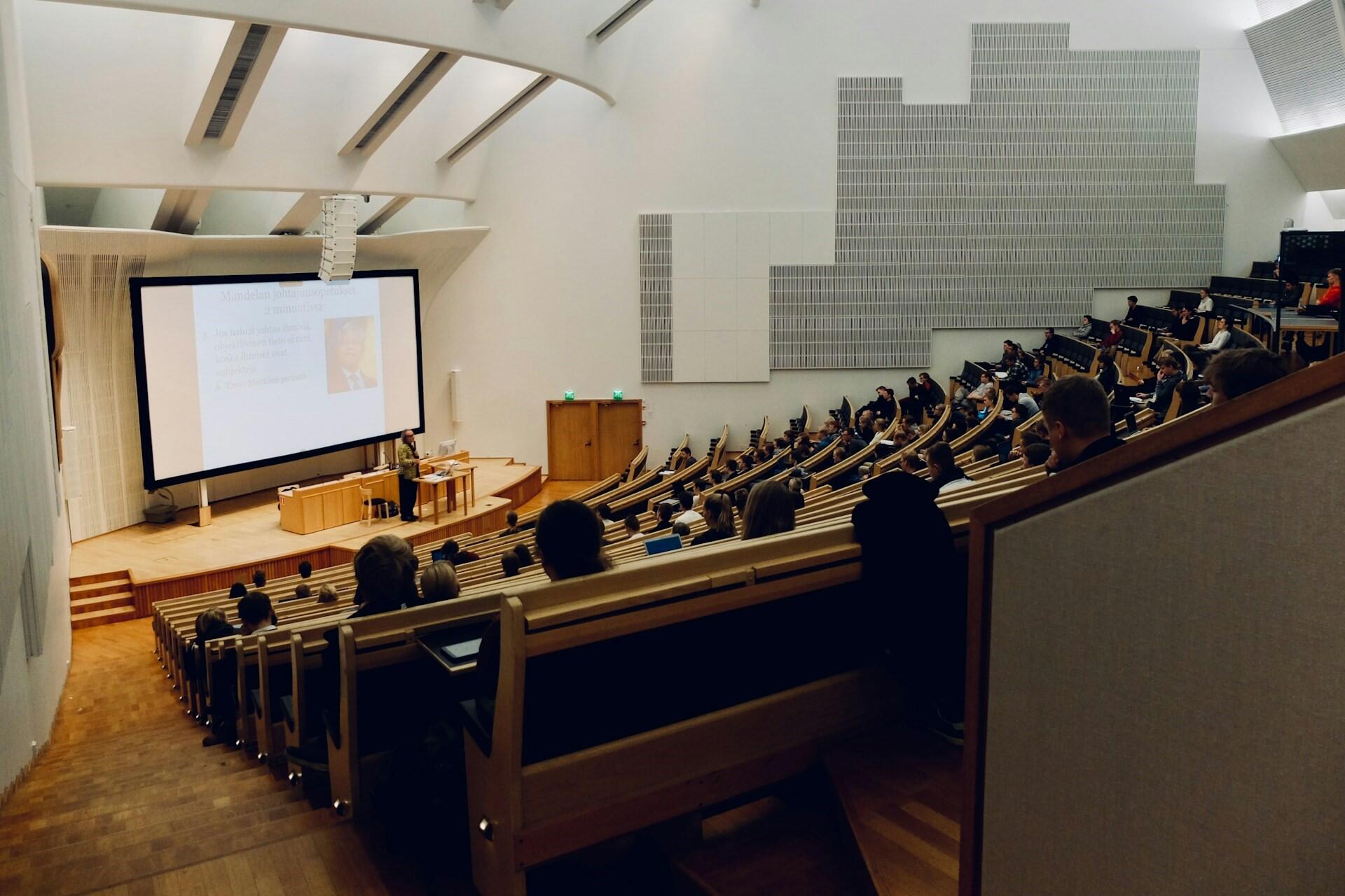Students sitting in a large university lecture hall during a presentation