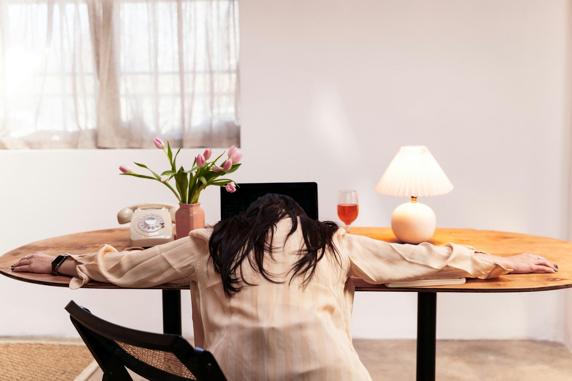 student sitting at a desk with a computer, completely slumped over, face down