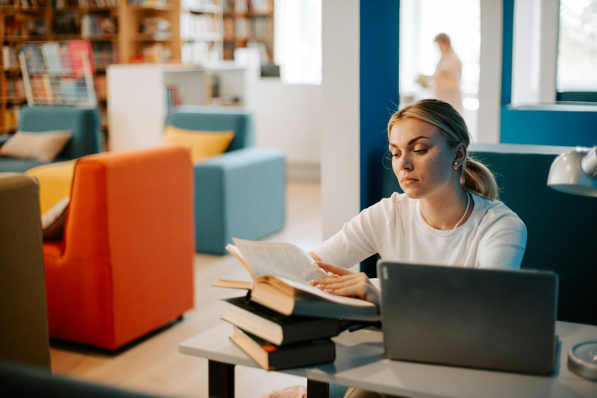 student studying with books and laptop in a library