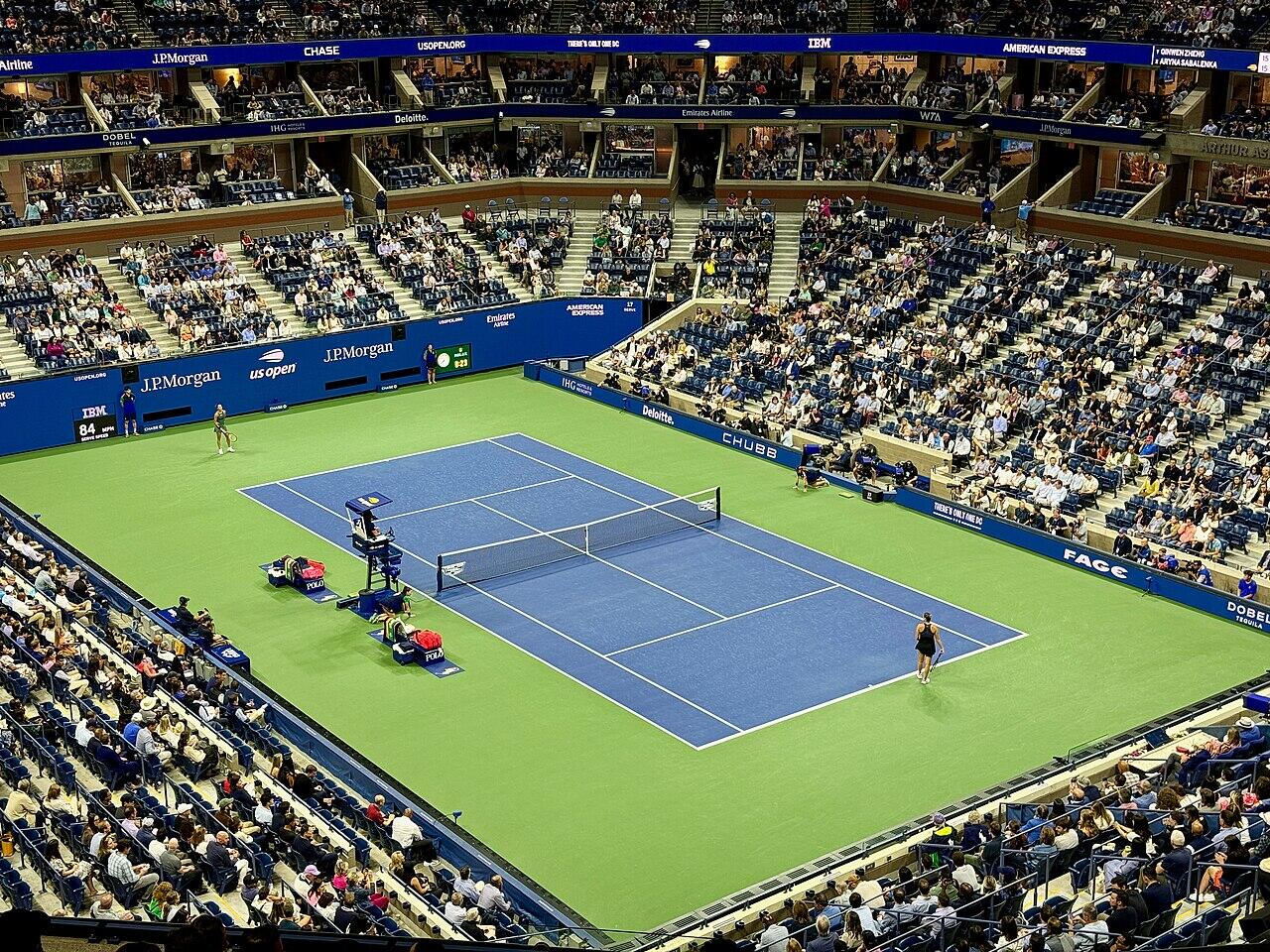 A tennis match playing at the US Open with fans sitting in the stands.