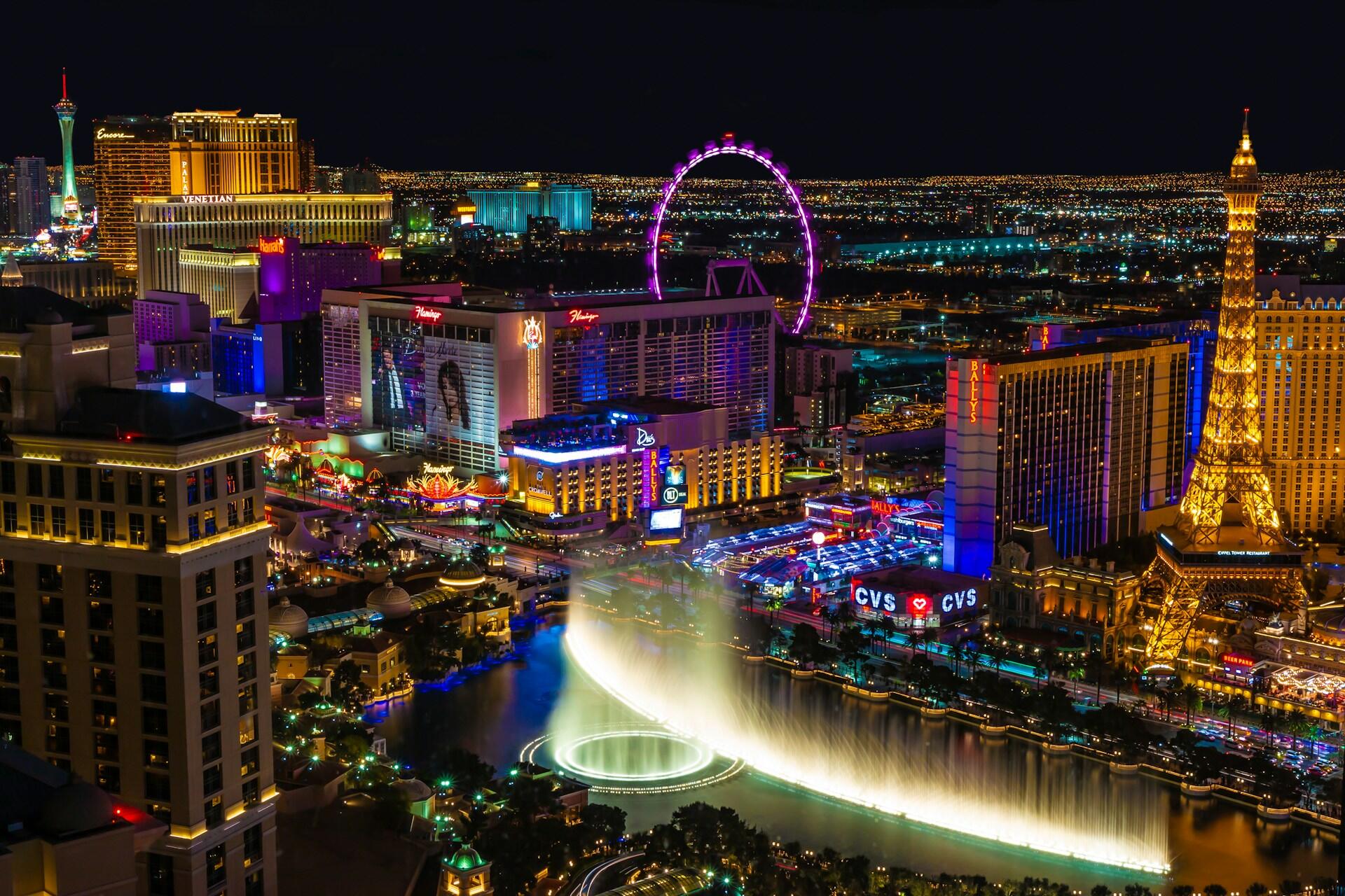 Las Vegas Strip at night with illuminated hotels, the High Roller, Eiffel Tower replica, and Bellagio fountains