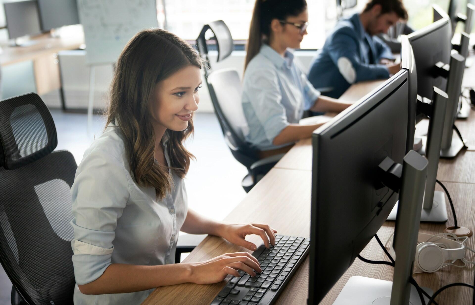 group of students sitting at their own computers in a large classroom