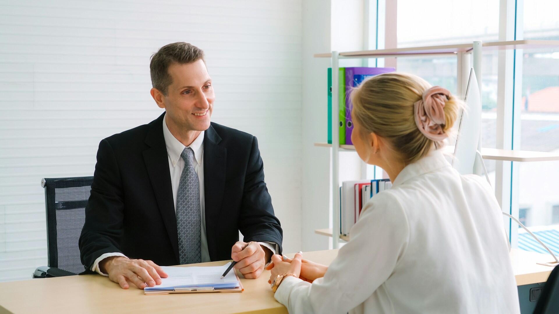 an interviewer asking an applicant questions in a brightly lit office
