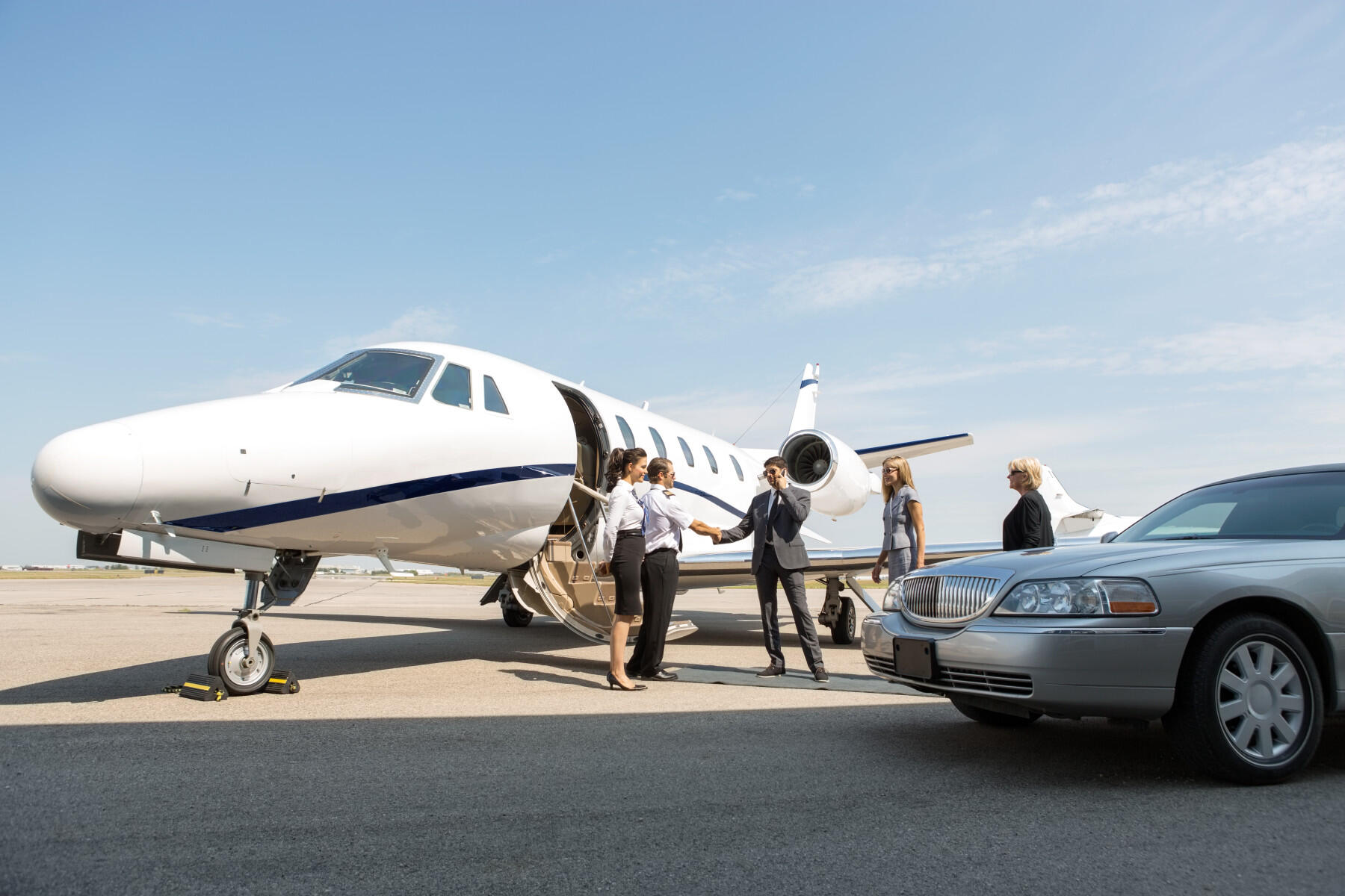 Commercial pilot welcoming guests onto private jet
