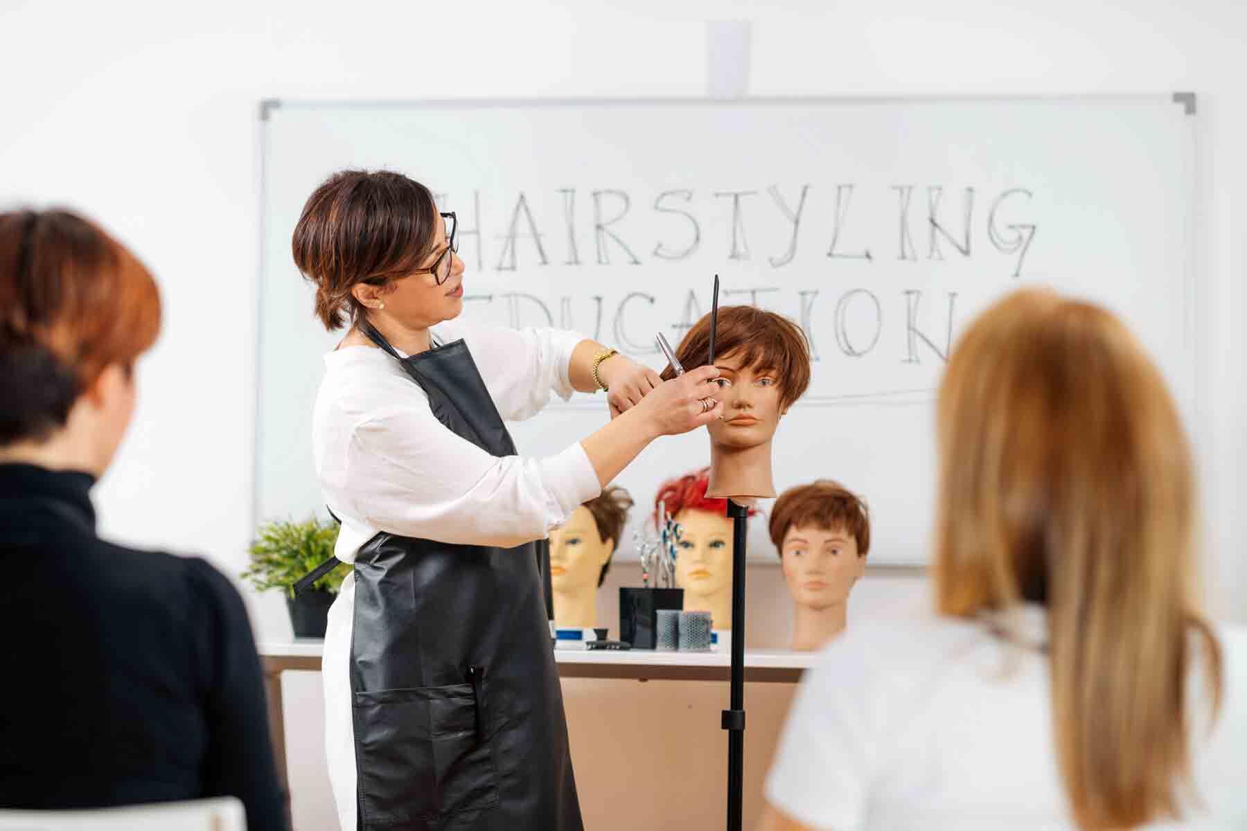 Instructor demonstrating hair cutting and styling techniques to students