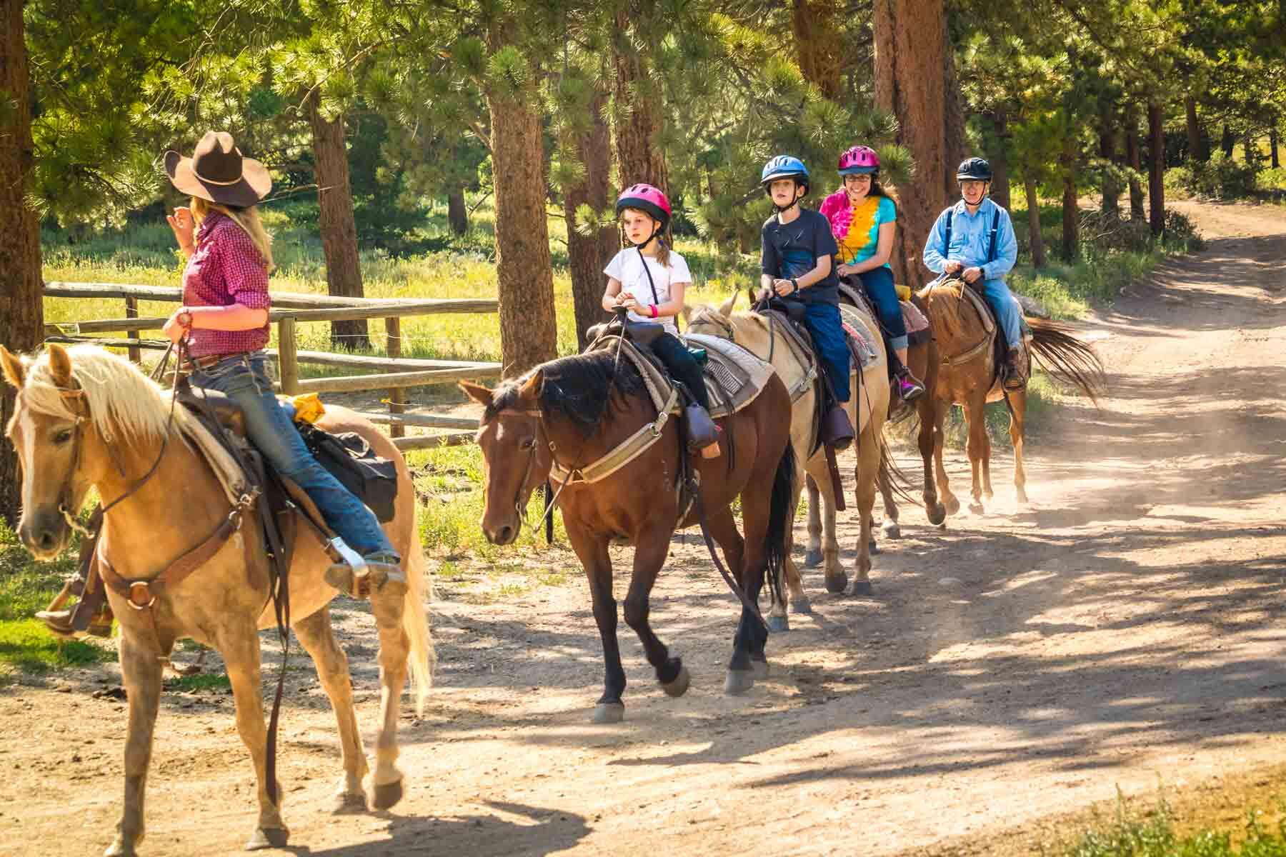 An instructor giving a family horseback riding lessons.