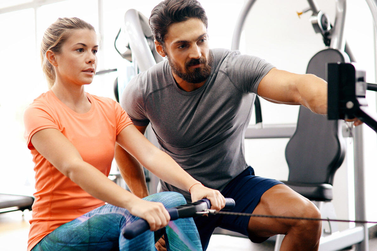 A personal trainer giving instructions to a woman in a gym
