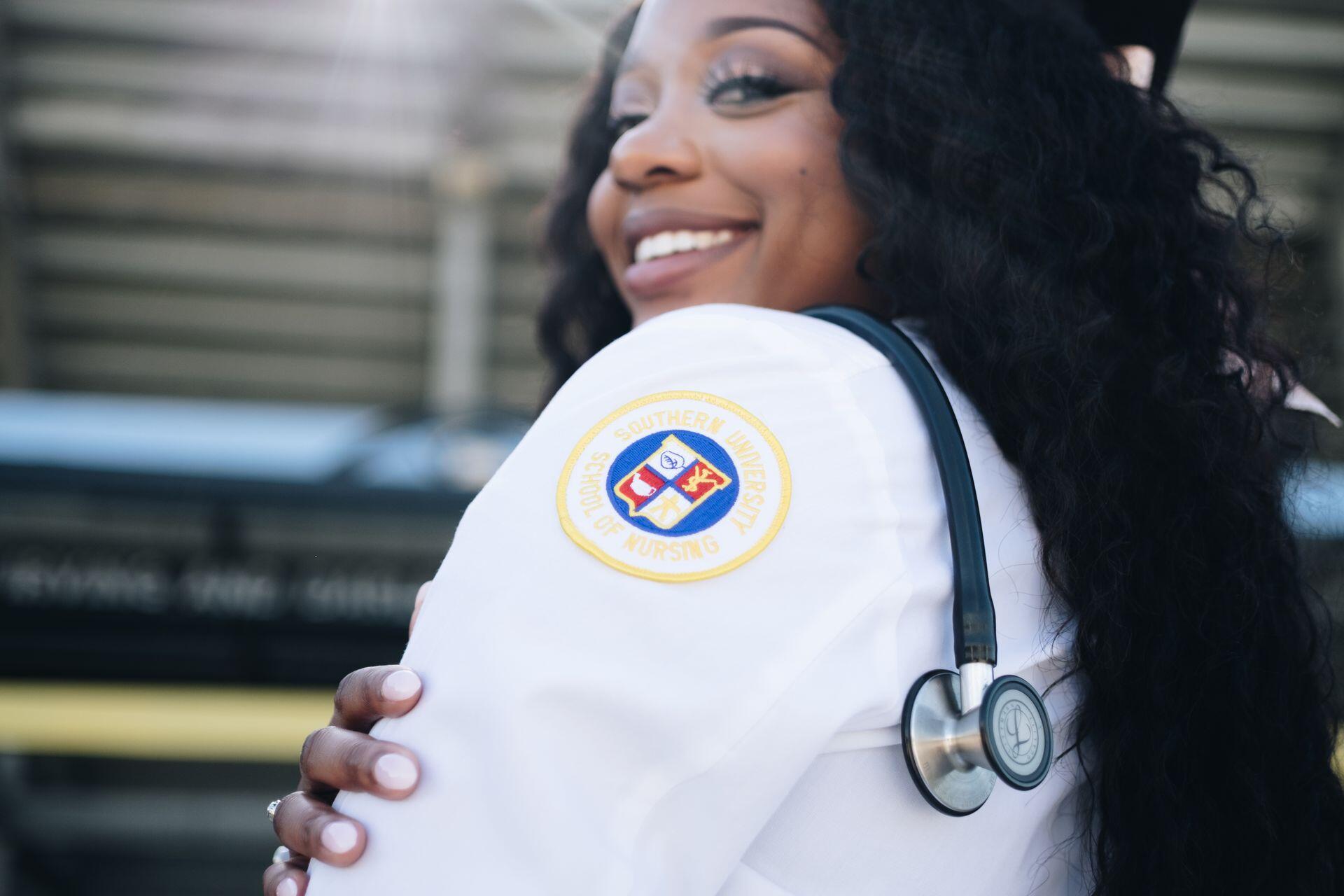 a medical school graduate smiling with their new lab coat and wearing a stethoscope