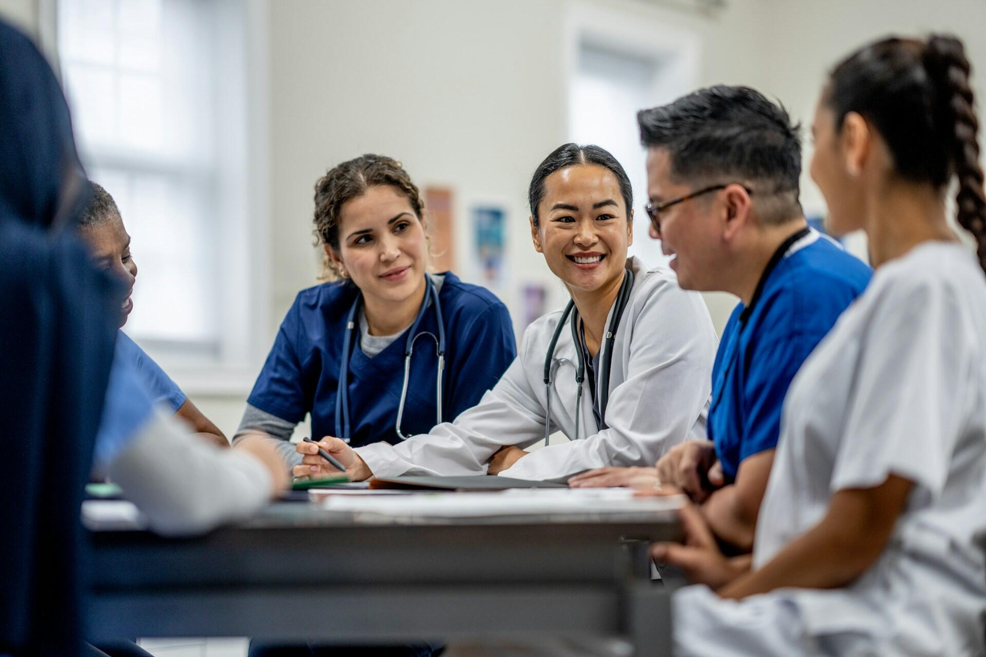 group of medical students and doctors sitting at a table and talking together