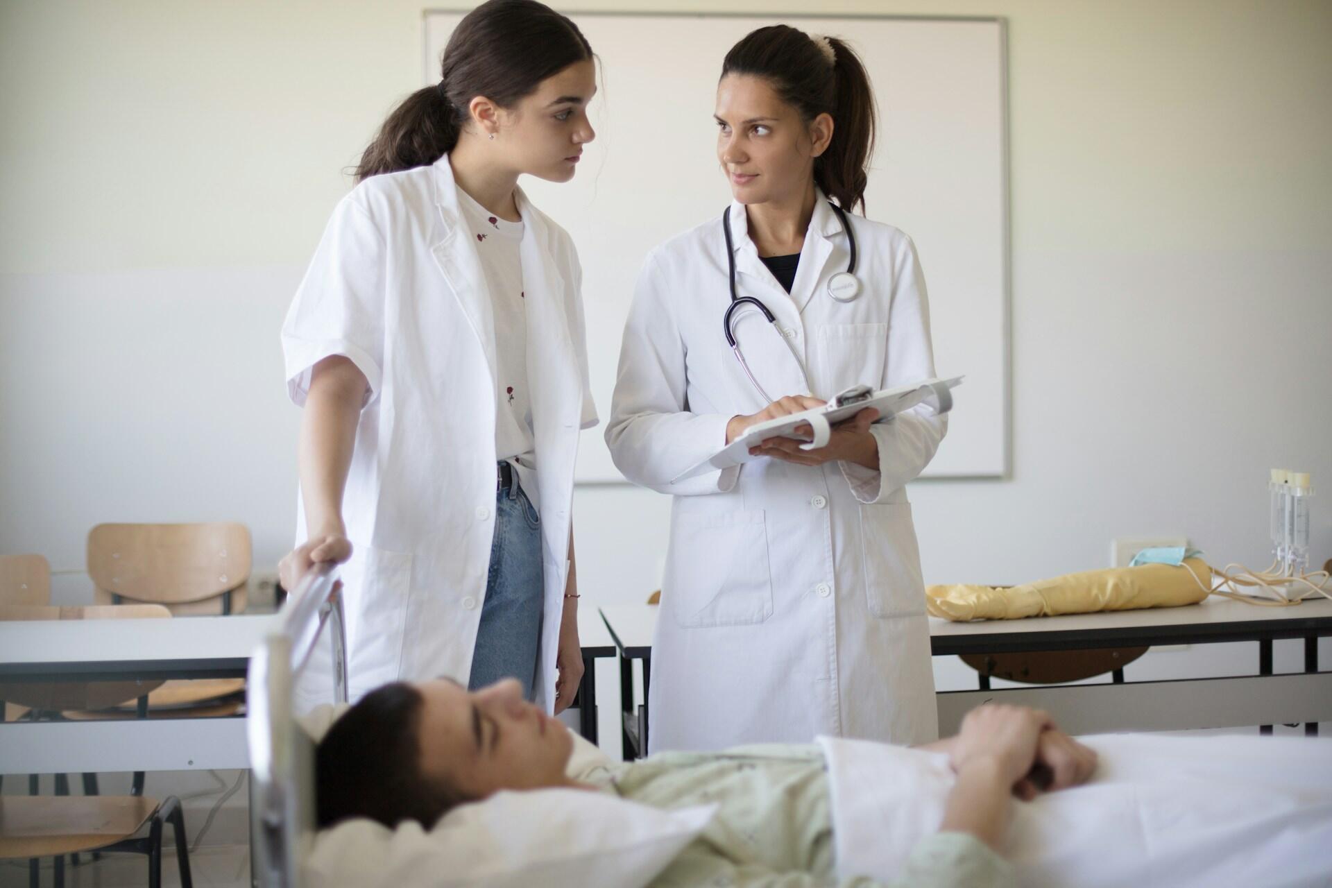 a young student shadowing a physician at a clinic, learning about reading patient charts