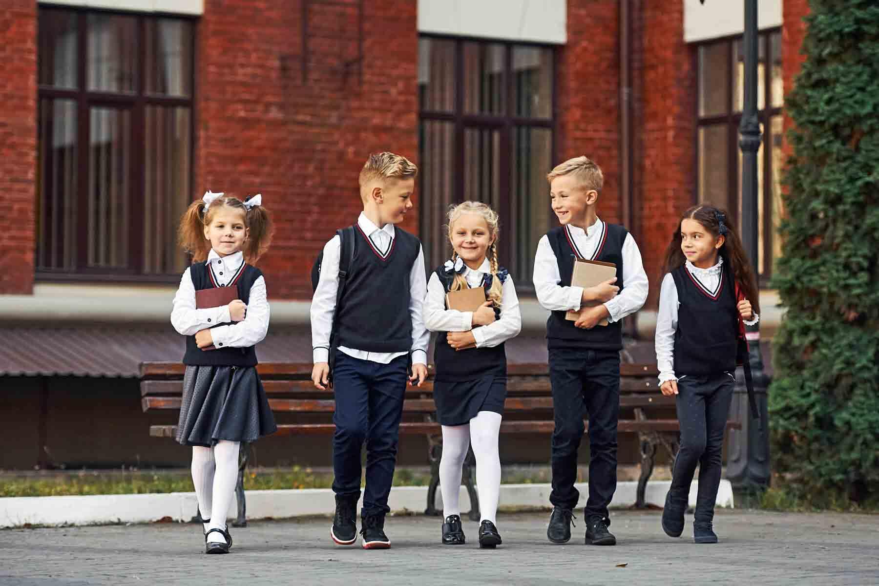 Young private school students in front of a school building.