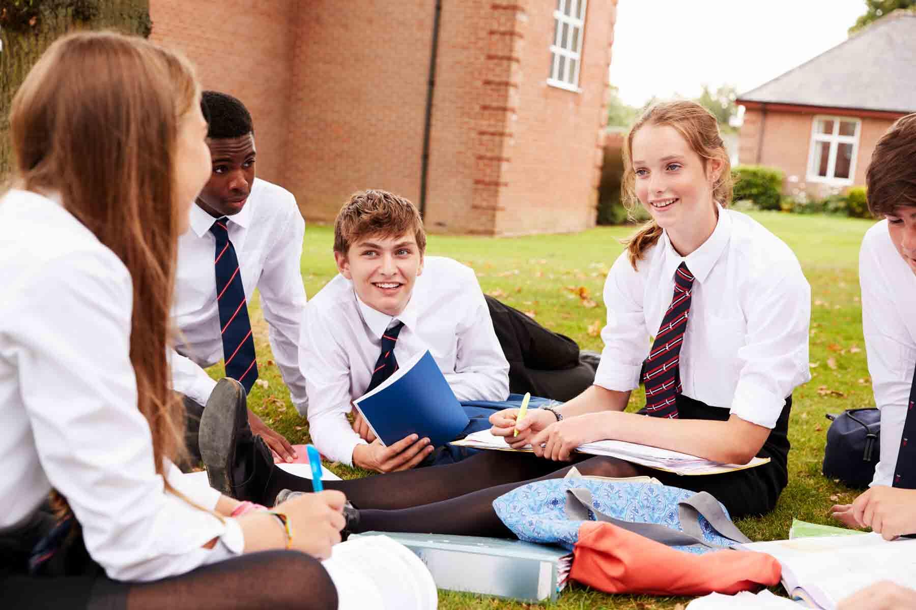 A group of private school students studying together outside.