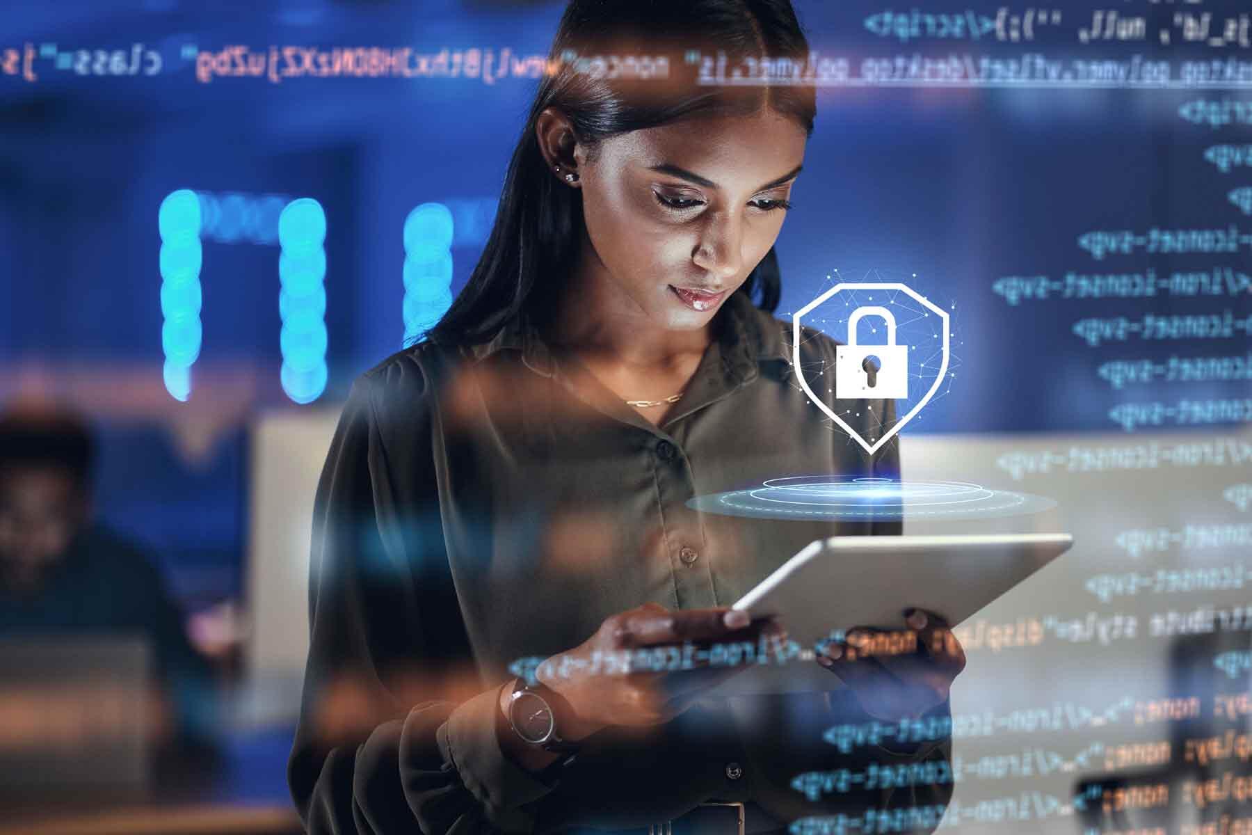 Information security manager reviewing a tablet with a padlock security icon and lines of code overlaid