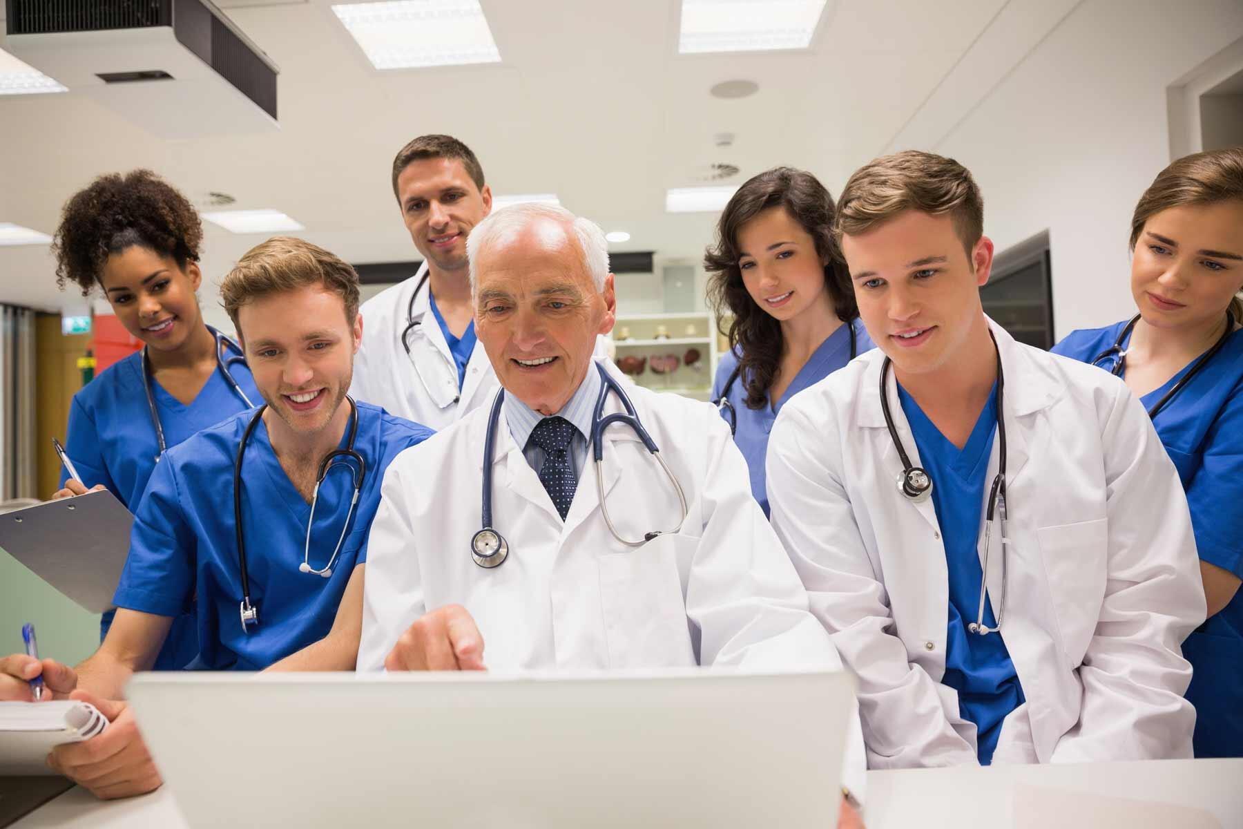 A professor showing information on a laptop to medical students.