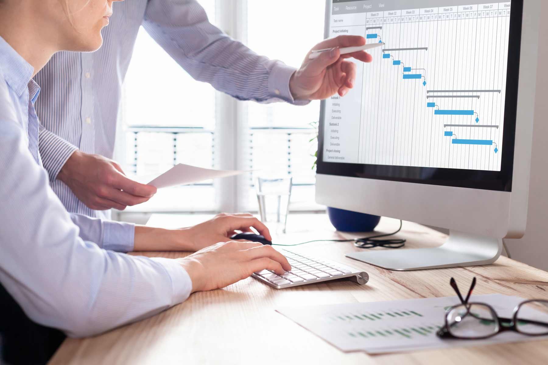 Project management team updating the schedule on a Gantt chart.
