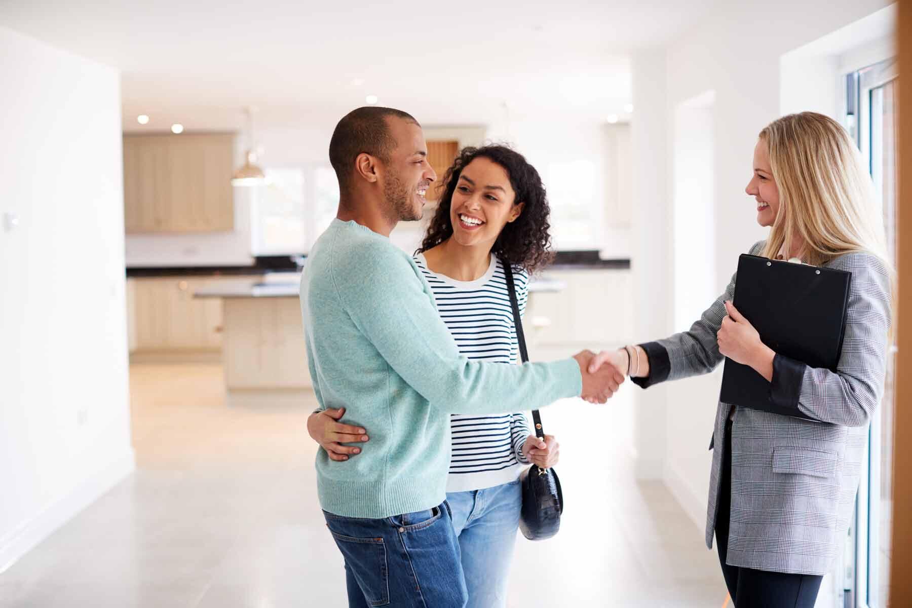Real estate agent shaking hands with a couple buying a new house