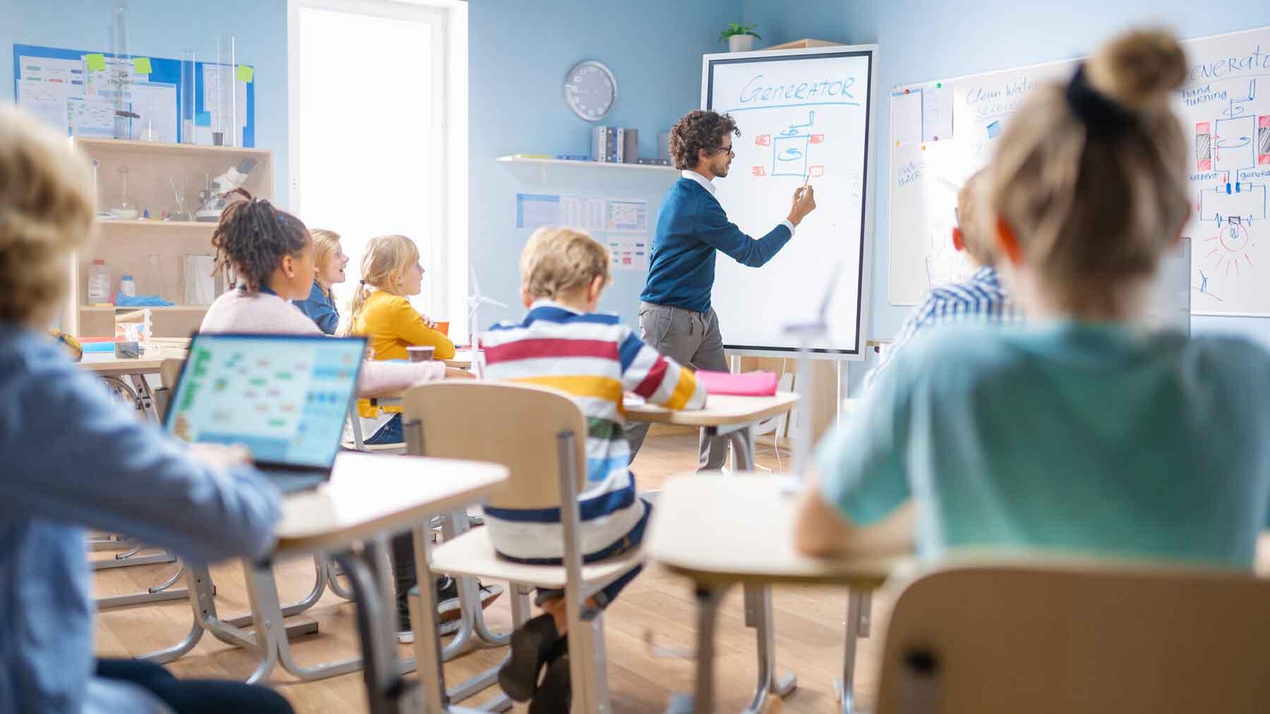 A teacher writing on a smart board in a classroom.