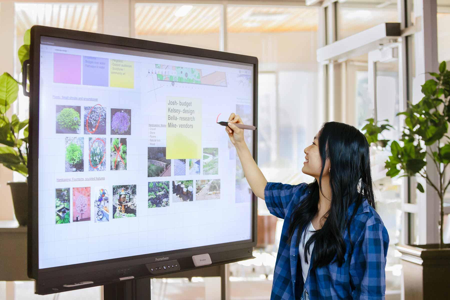A woman using a Promethean smart board panel for project planning
