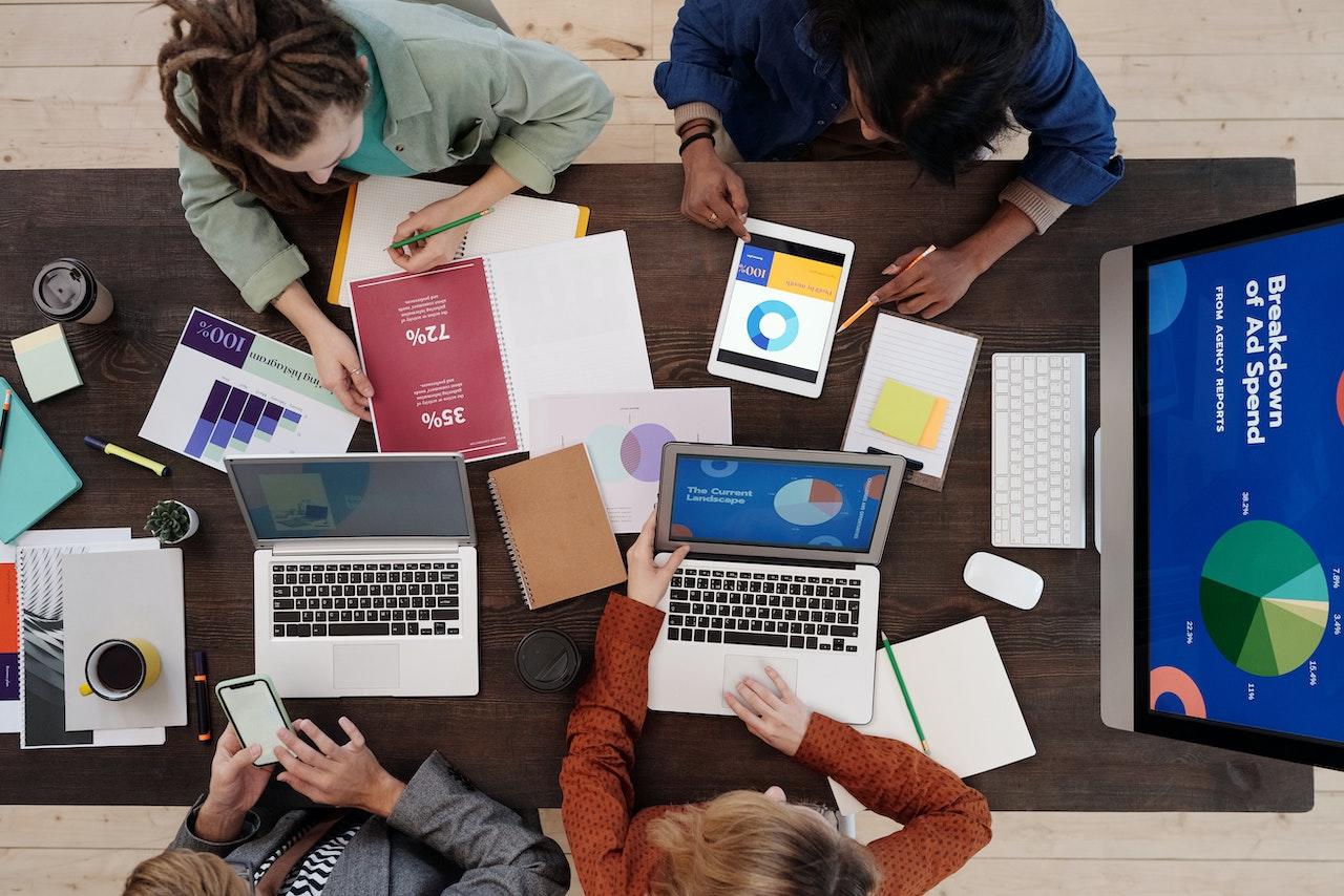 Grupo de trabajo reunido en una mesa con sus computadoras y cuadernos.