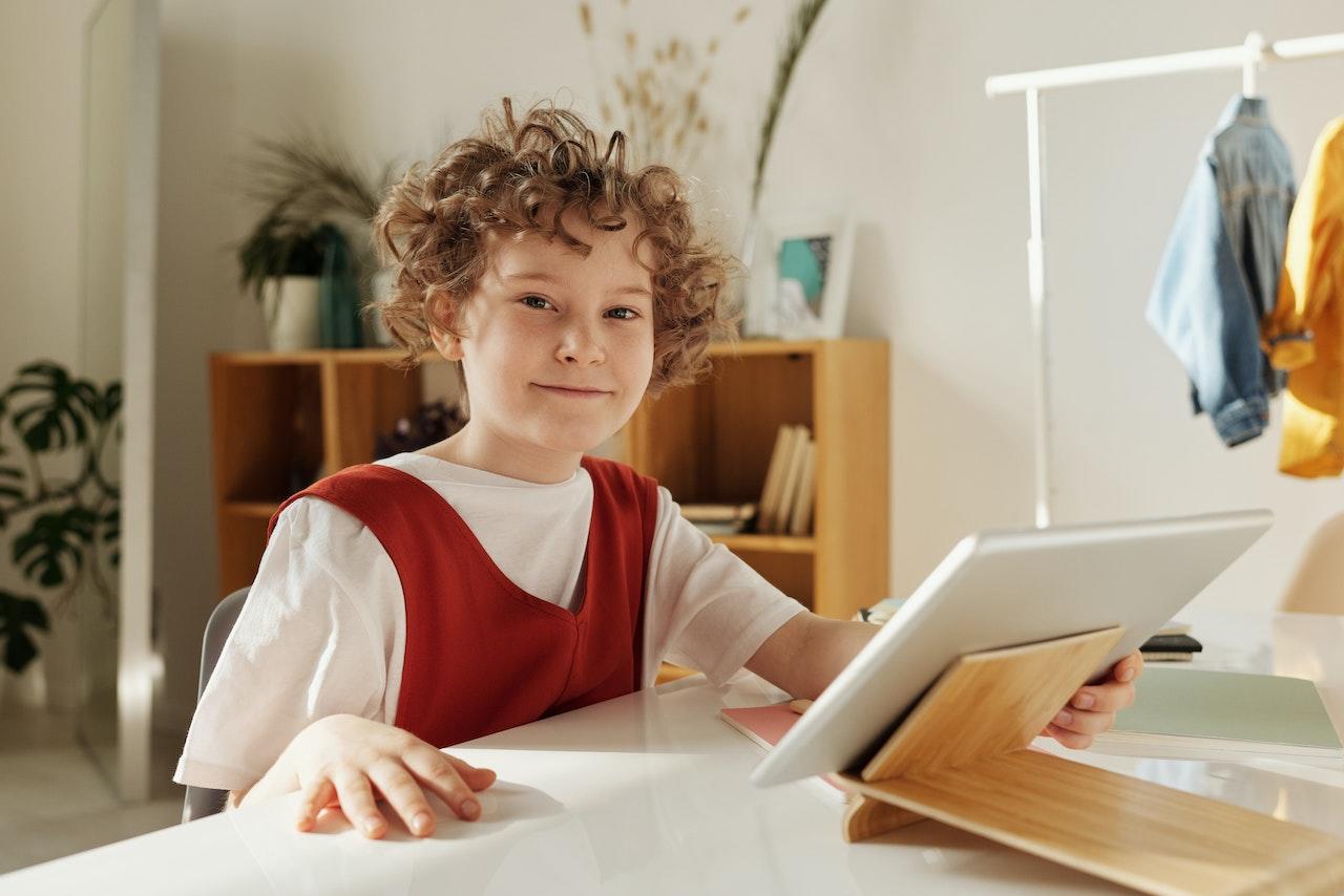 Niña estudiando junto a su tablet.