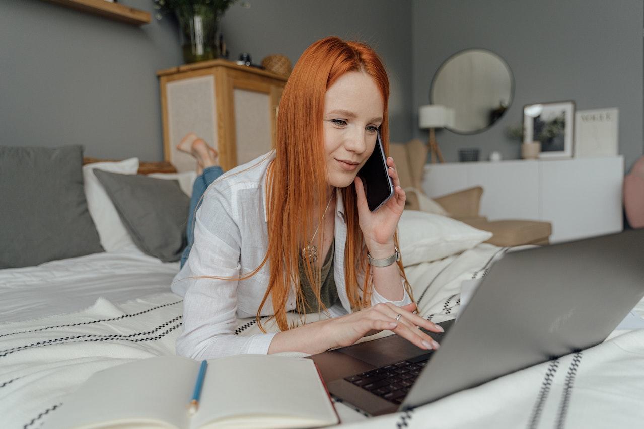 Mujer utilizando la computadora y llamando por telefono