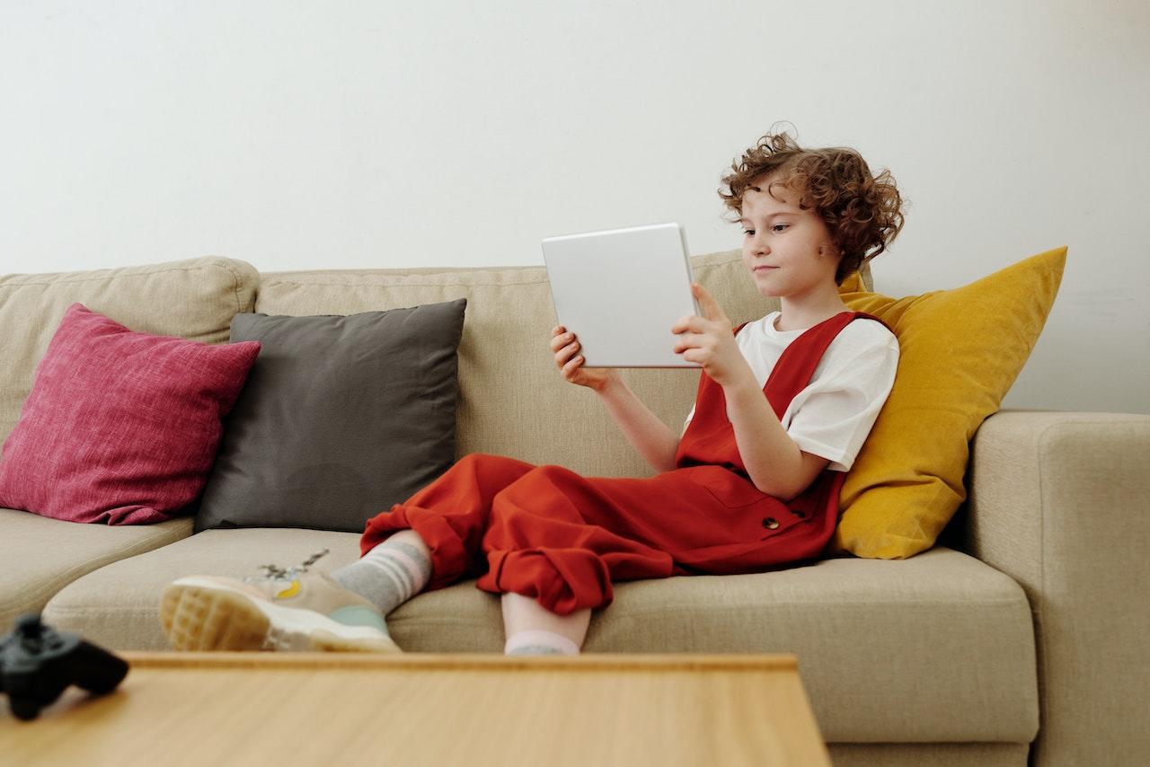 Niña en el sillón jugando con la tablet
