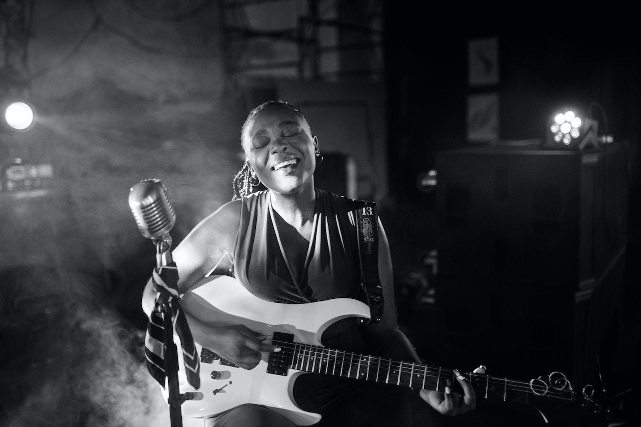 Mujer cantando y tocando la guitarra.