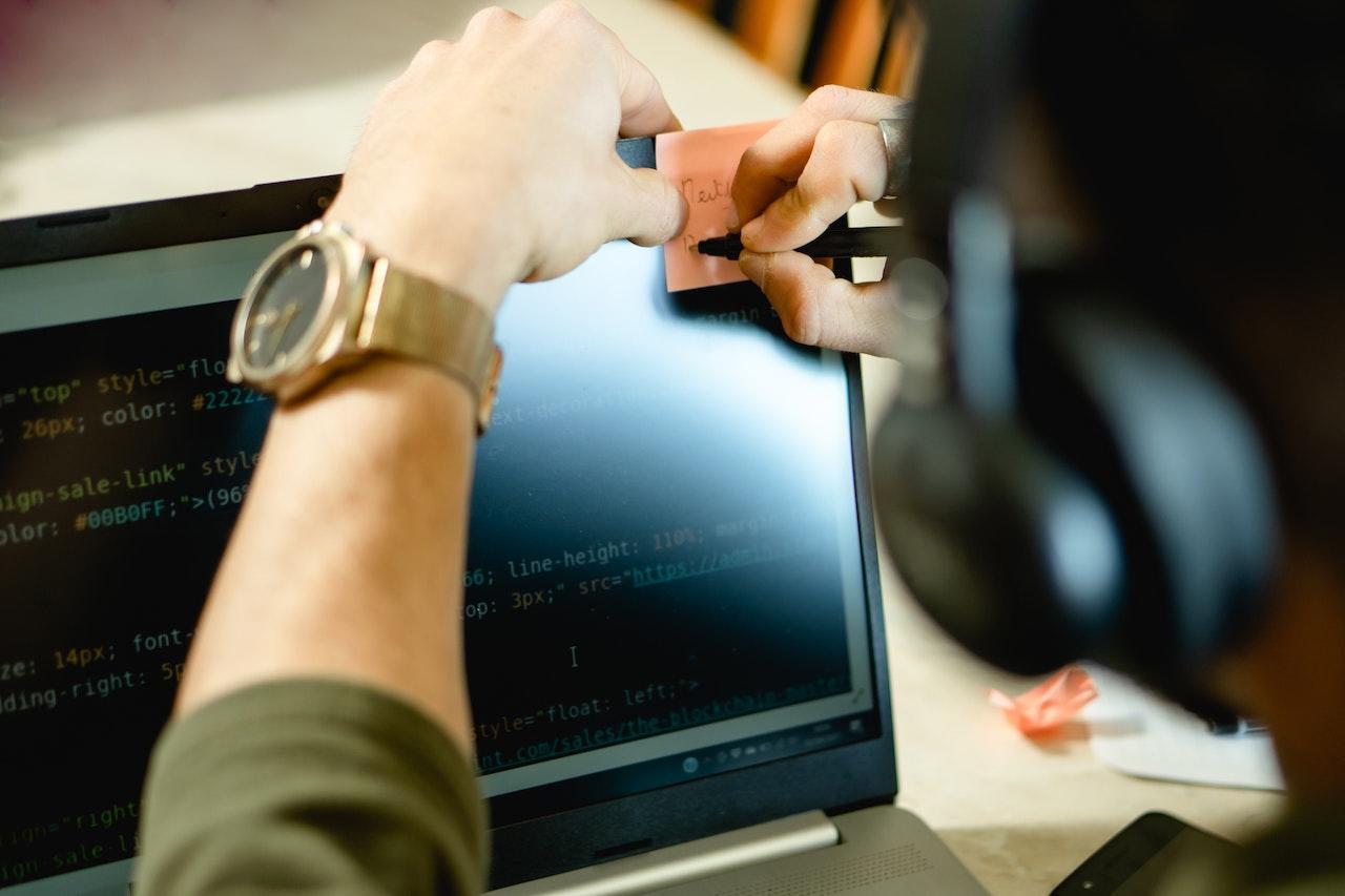 Persona anotando en papel al mirar la pantalla de programación 