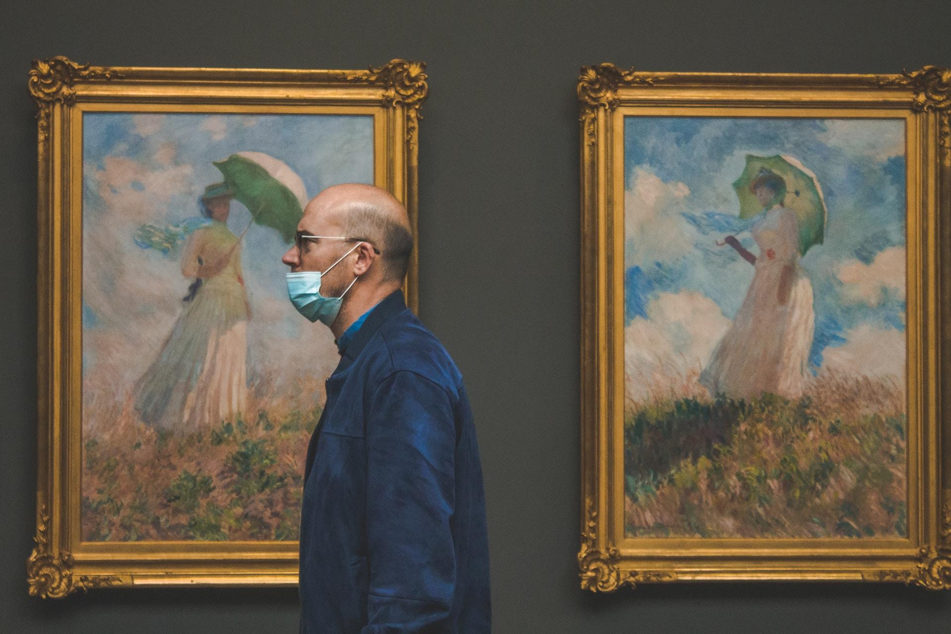 Hombre caminando en museo con cuadros de Monet de fondo