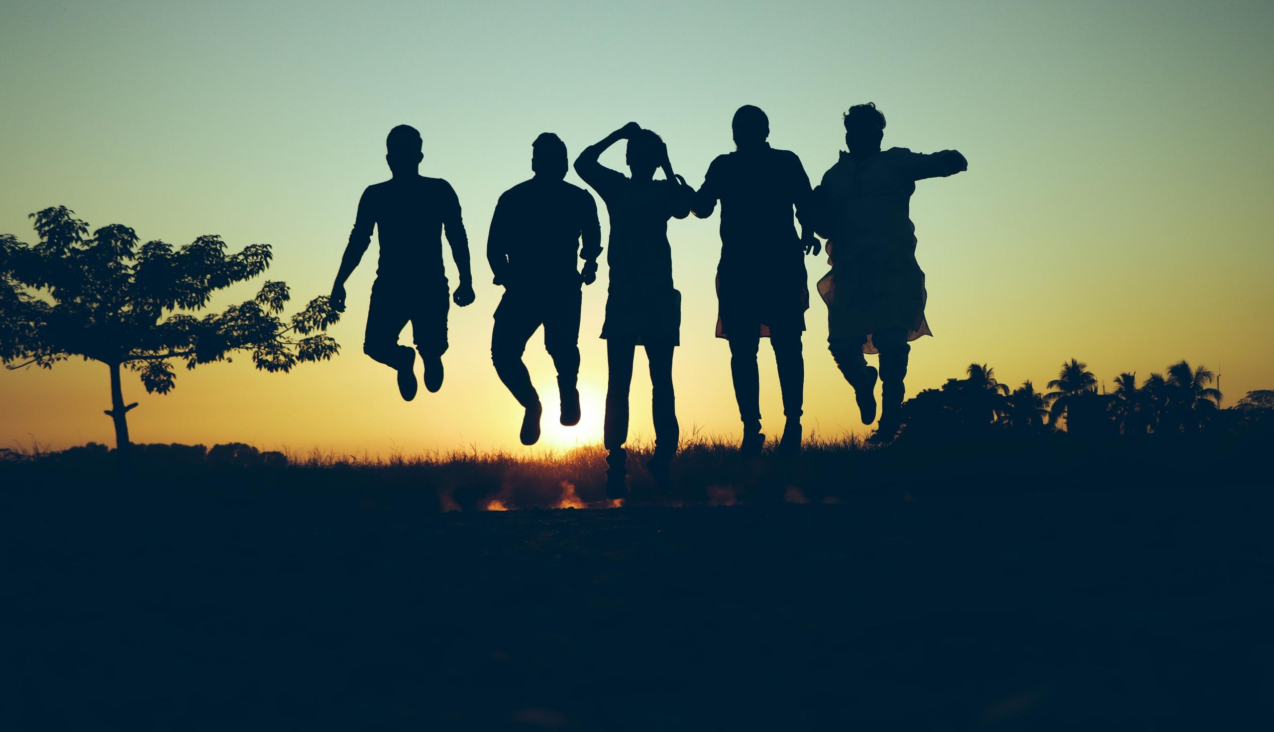 Personas saltando con el atardecer de fondo