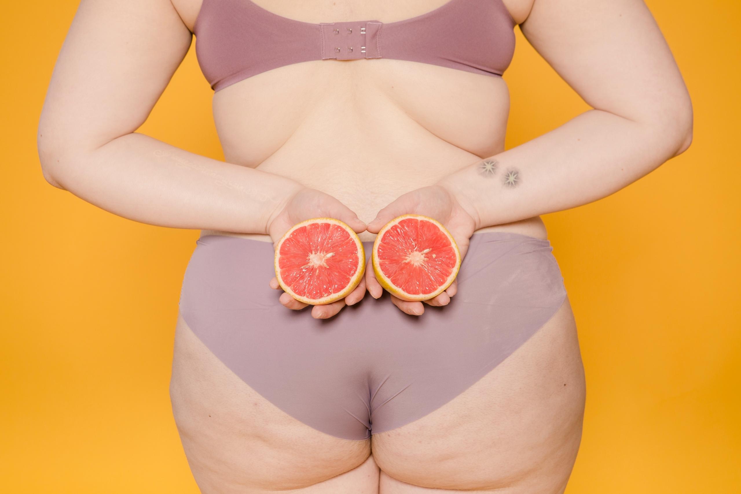 Mujer de espalda con dos pomelos en la mano