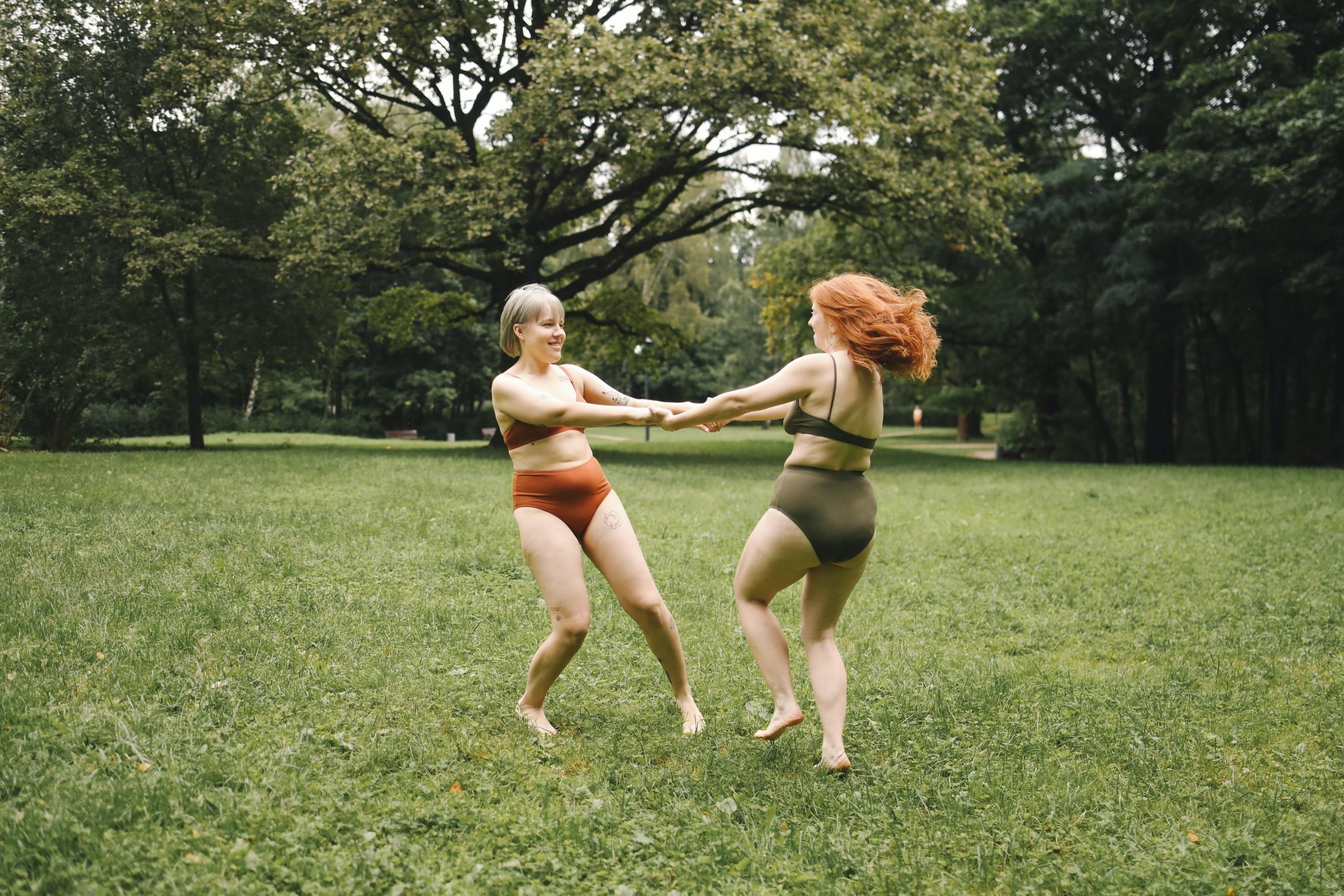 Dos mujeres saltando en bikini en un campo.