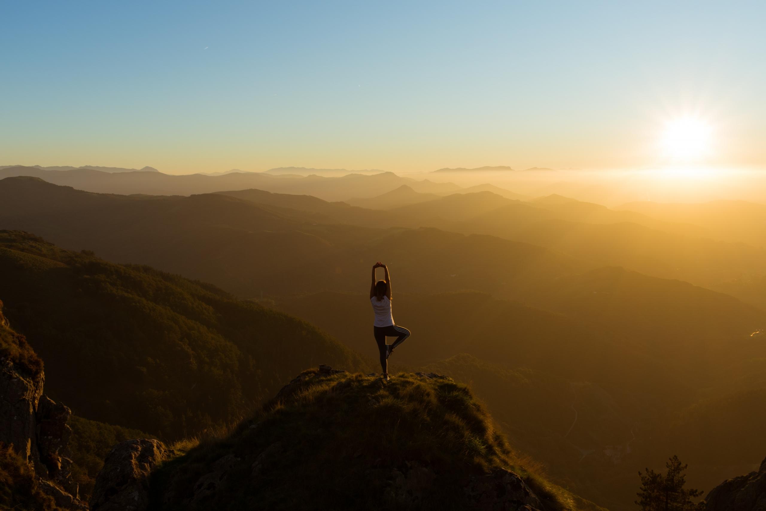 persona haciendo yoga en una montaña