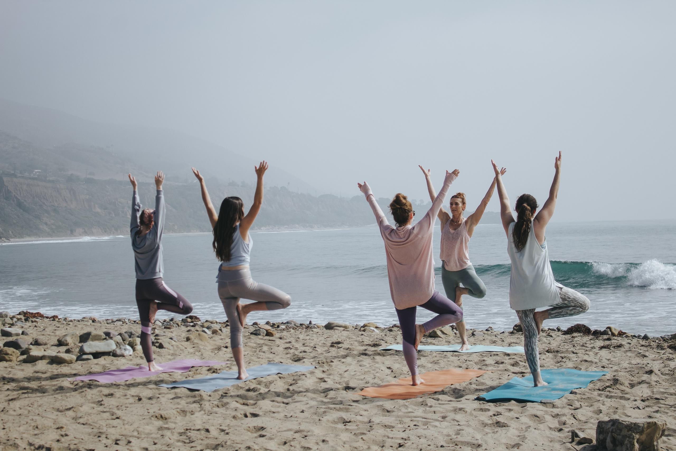 personas en una clase de yoga en la playa