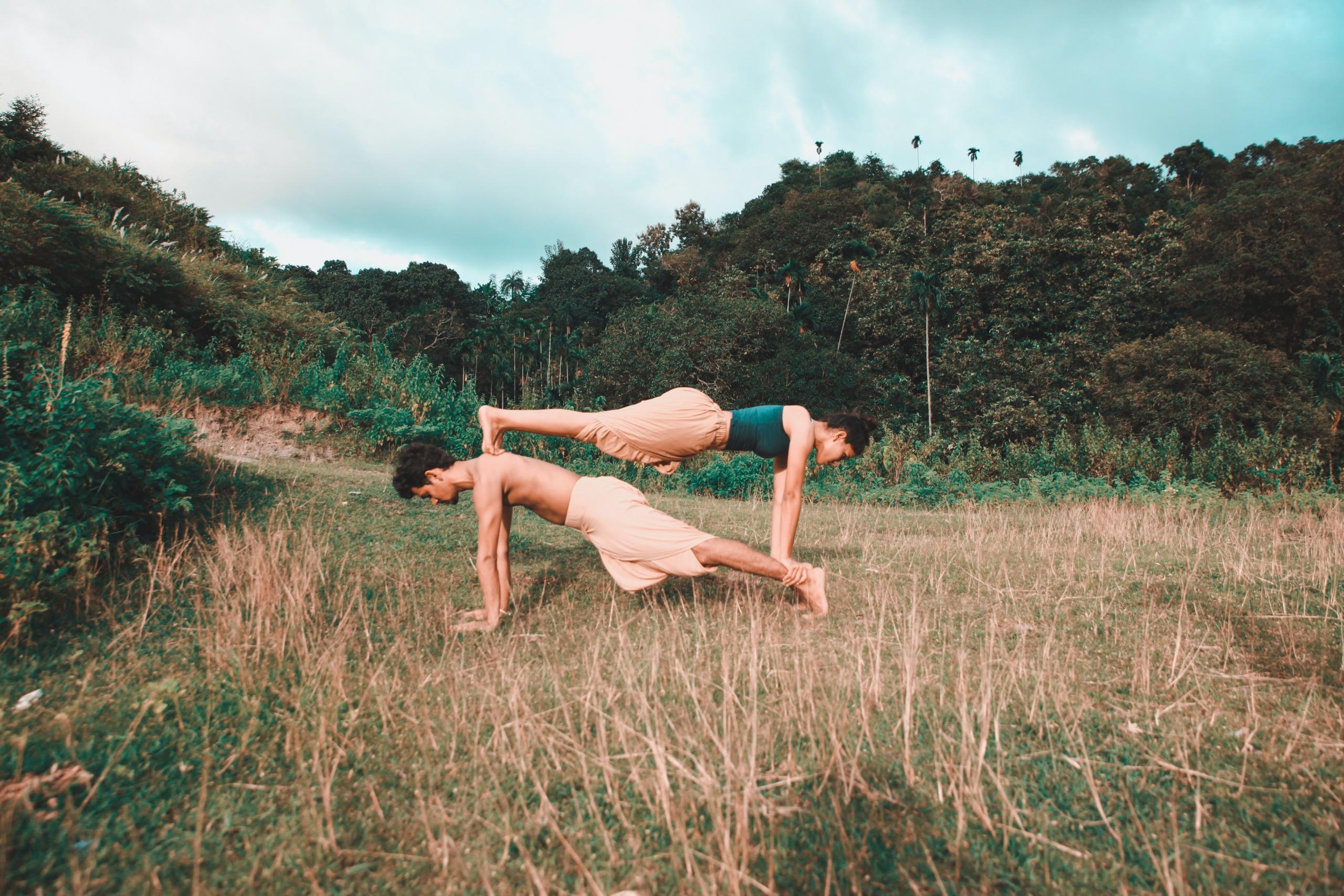 Dos personas practicando yoga en un campo