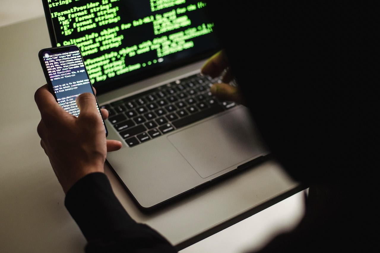 persona con el celular y la computadora en programación
