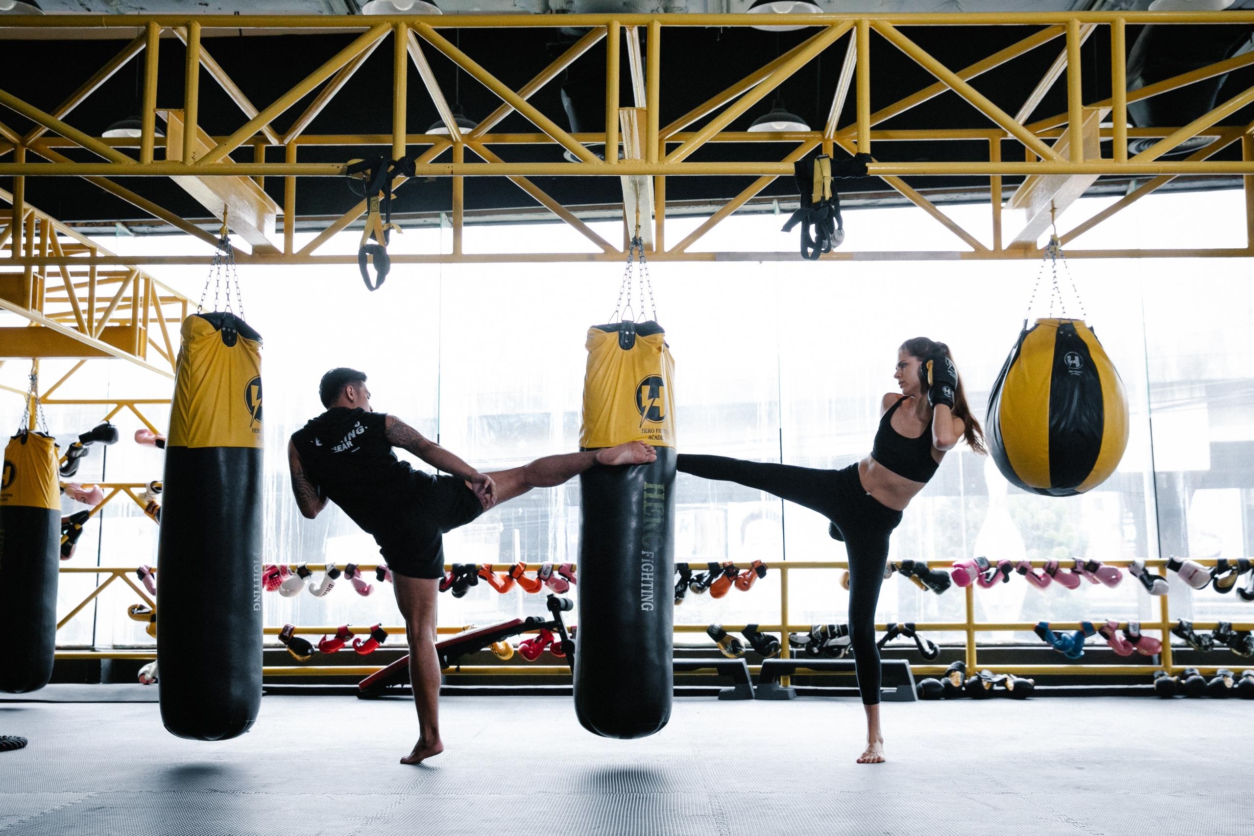 dos personas entrenando con una bolsa de boxeo
