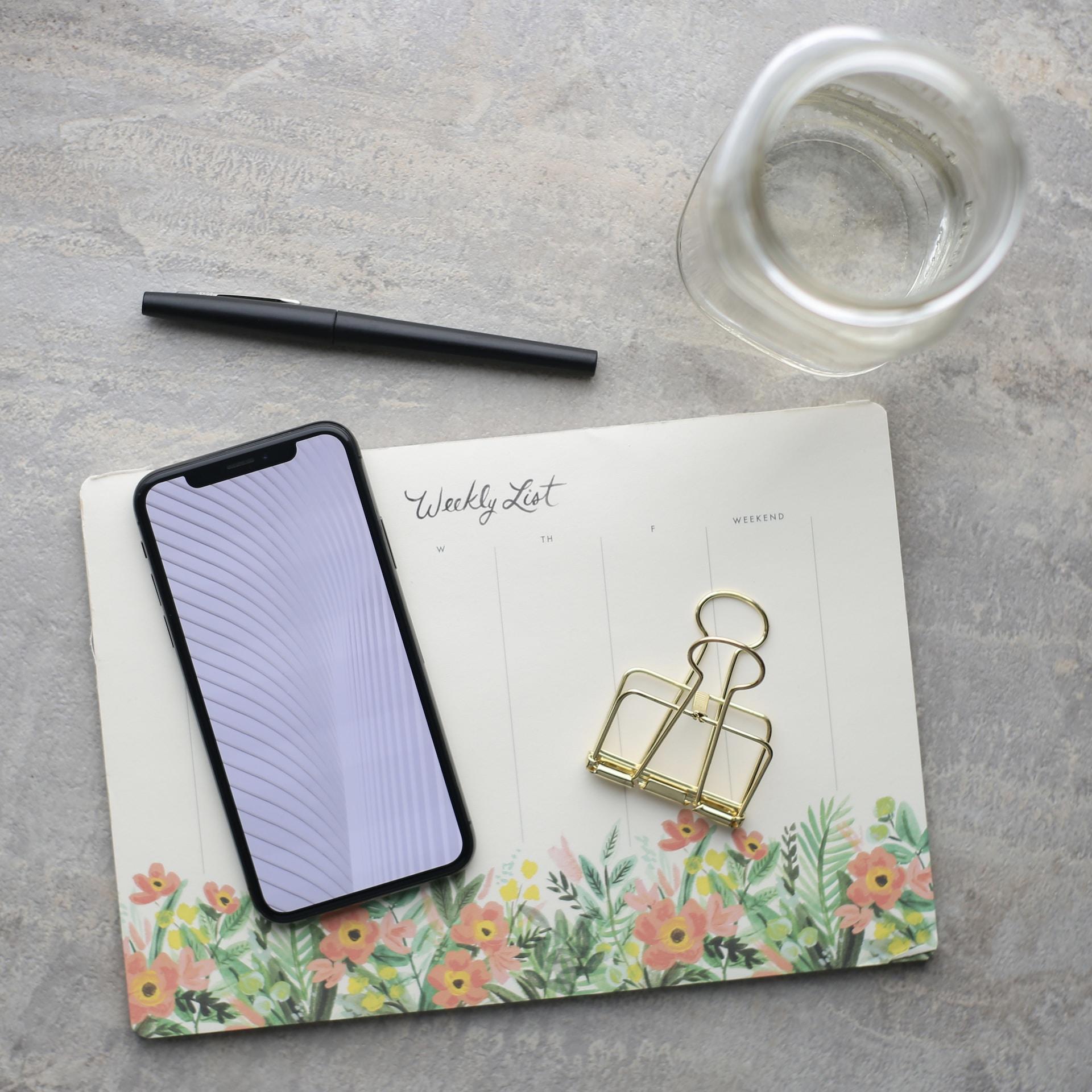 Celular, agenda y vaso de agua